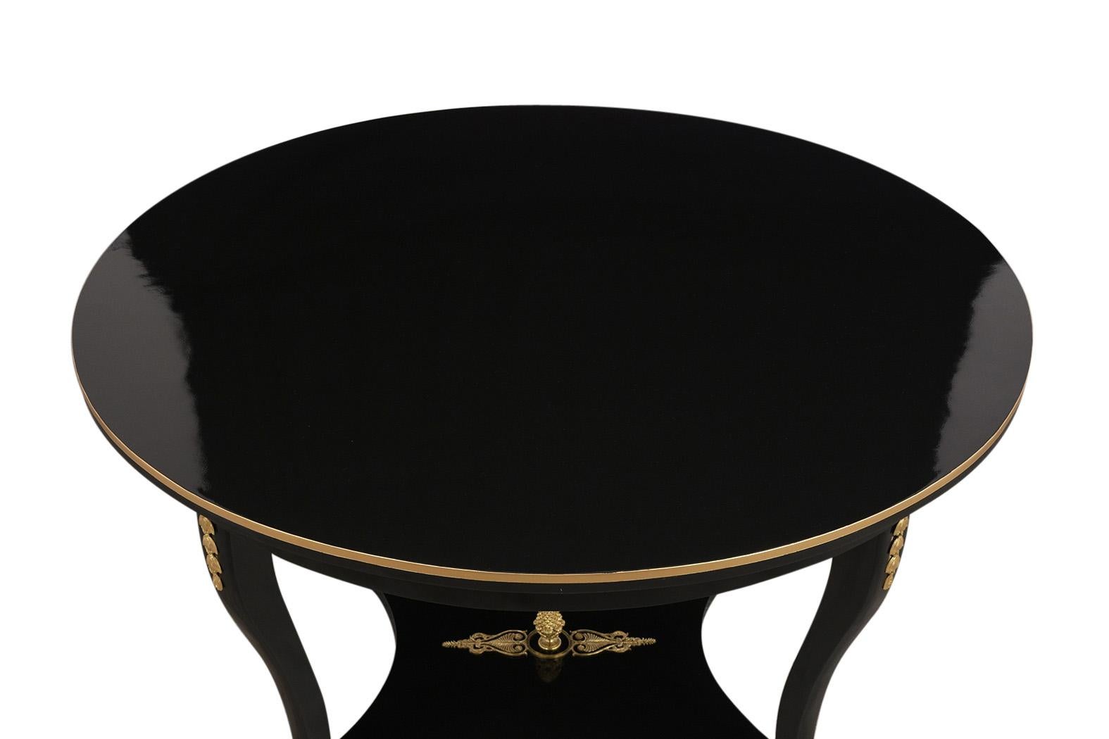 This Late 19th-Century Grand Regency Center Table has been newly restored and is made out of mahogany wood and has a newly ebonized lacquered finish with gold trim details. This table features beautiful brass decorations along the side, center,