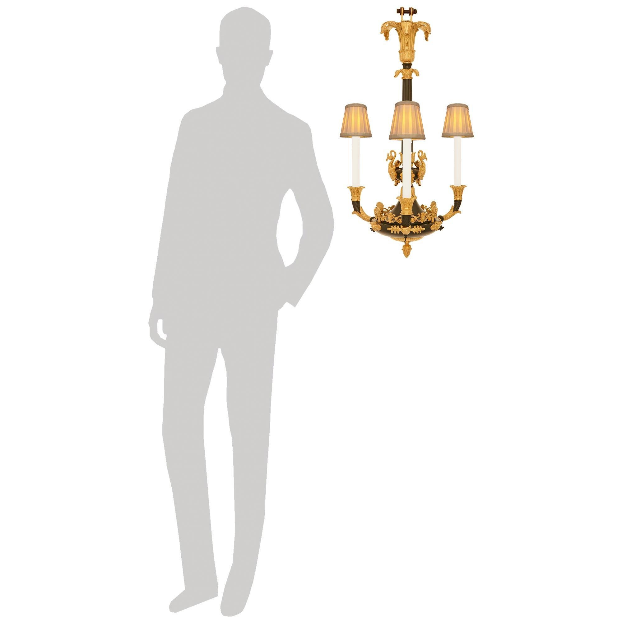 Un elegantissimo e sofisticato lampadario francese del XIX secolo in bronzo patinato e Ormolu. Questo stupendo lampadario a tre bracci è centrato da un terminale a ghianda in Ormolu finemente cesellato e da una montatura a gadroon che conduce a una