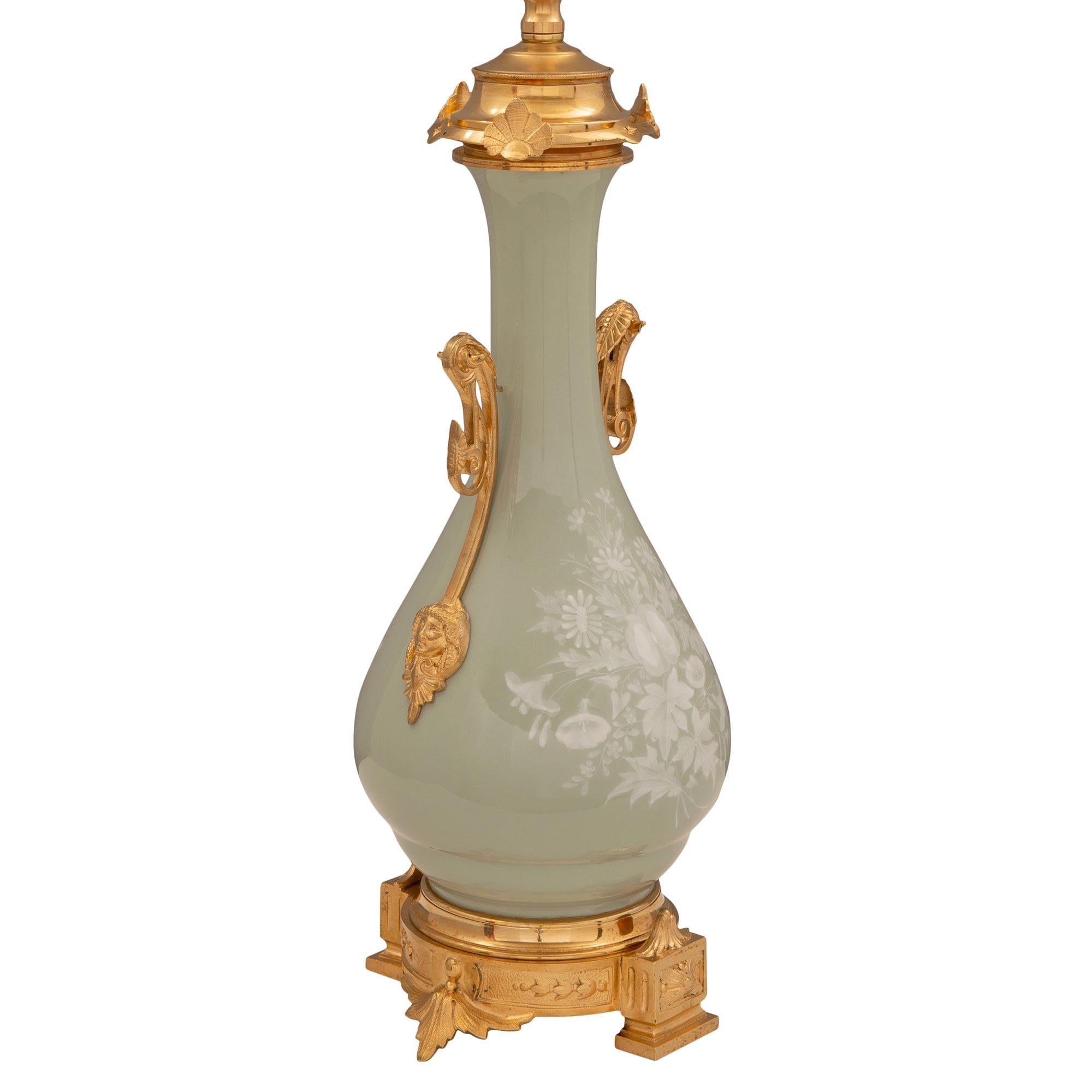 A beautiful and extremely decorative French 19th century Renaissance st. Pâte sur Pâte celadon colored porcelain and ormolu lamp. The lamp is raised by a beautiful finely detailed circular ormolu base with mottled block feet at the front and back