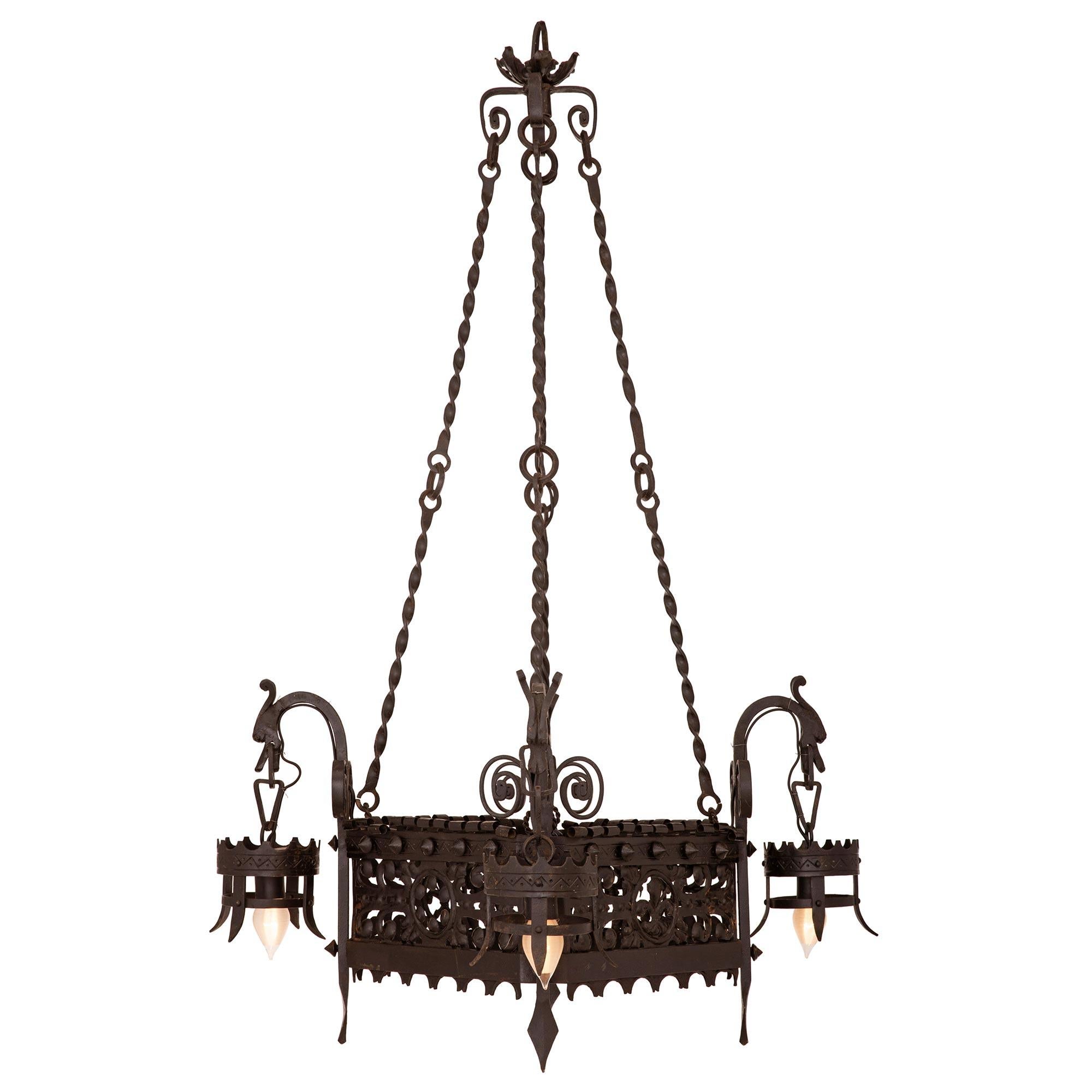 A beautiful French 19th century Renaissance st. wrought iron chandelier. The four arm five light chandelier displays a single hanging light bulb centered by beautiful scrolled pierced wrought iron designs with four striking circular torch like