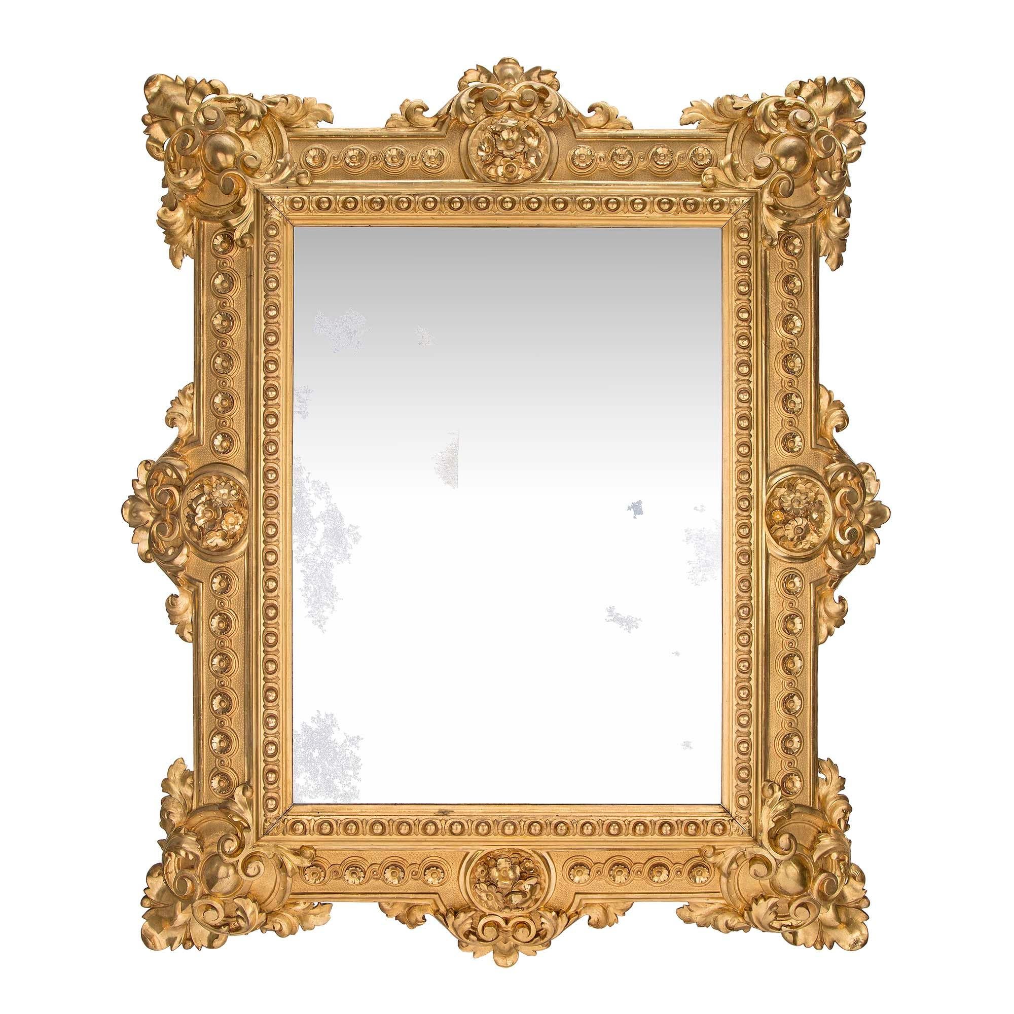 A striking French 19th century Renaissance st. finely carved giltwood mirror. This remarkable mirror has the original mirror plate and is framed within an inner beaded border with circular floral reserves. Each corner and side is opulently decorated