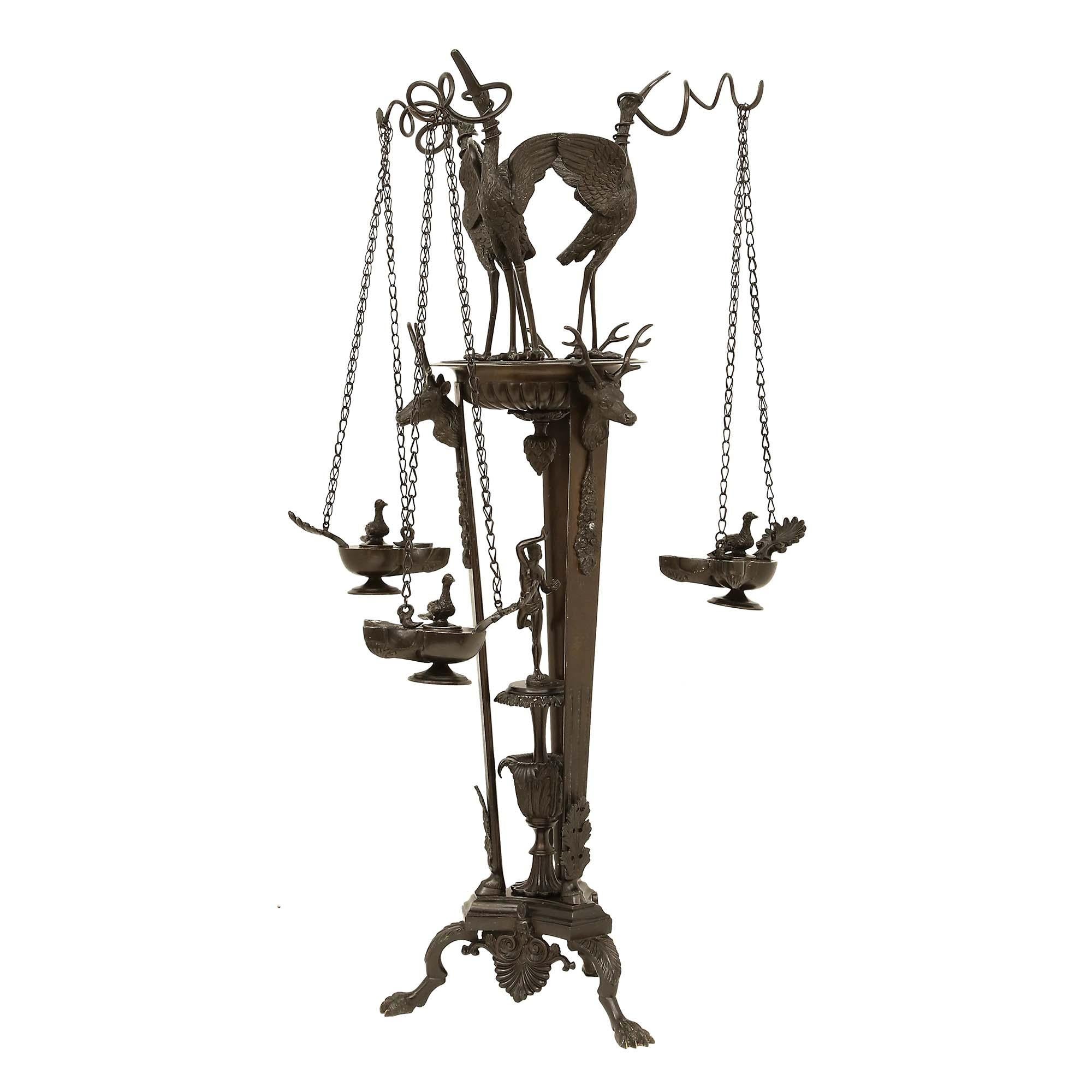 Lampe à huile sur pied en bronze patiné, extrêmement décorative, datant de la Renaissance française du 19e siècle. Le support a une base tripode avec des palmettes, et des côtés concaves, centrés par une urne avec une plateforme et une figure