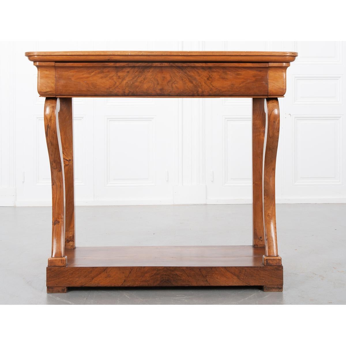 This gorgeous walnut console was made in France, c. 1860. The solid wood top has rounded front corners and is original to the console. Below the top, a hidden drawer is housed in the table’s shaped apron. The drawer front and front of the base have