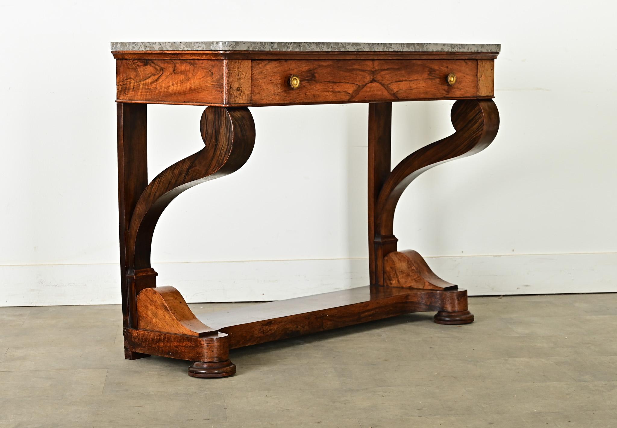 A handsome walnut console made in the Restauration Period with a marble top. The stone top features spotted gray, monochromatic marbling with flat edges and rounded front corners. The apron is a wide drawer with bookmatched veneer drawerfront,