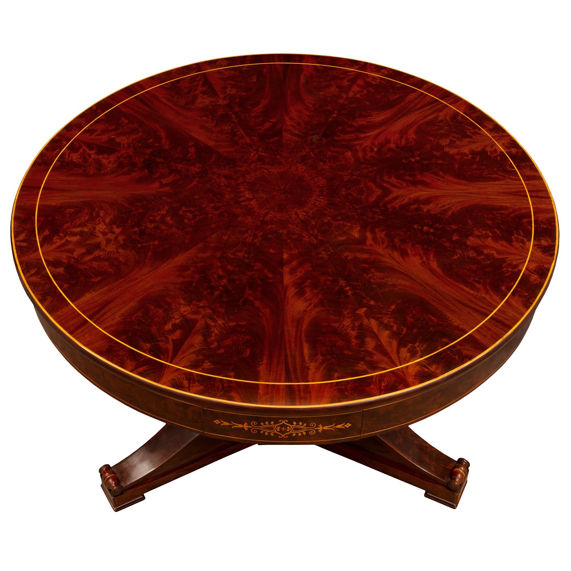 A beautiful and most decorative French 19th century Charles X period flamed Mahogany and Maplewood center table. The four drawer circular center table is raised by three elegant scrolled legs with their original casters below the impressive baluster