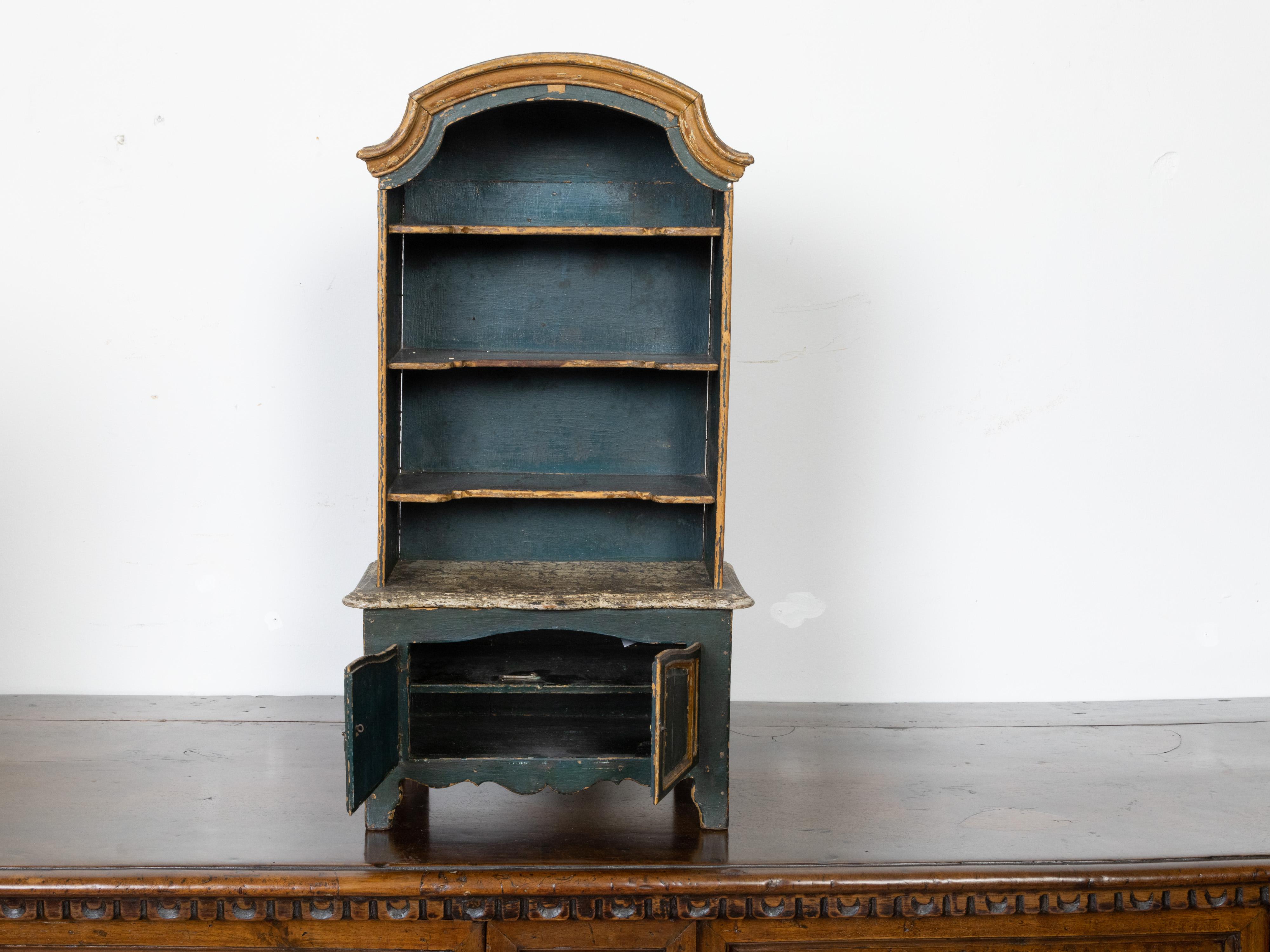 A French Rococo style miniature painted cabinet from the 19th century, with arching top, open shelves and two doors. Created in France during the 19th century, this miniature cabinet will make for a great decorative addition to any child's room!