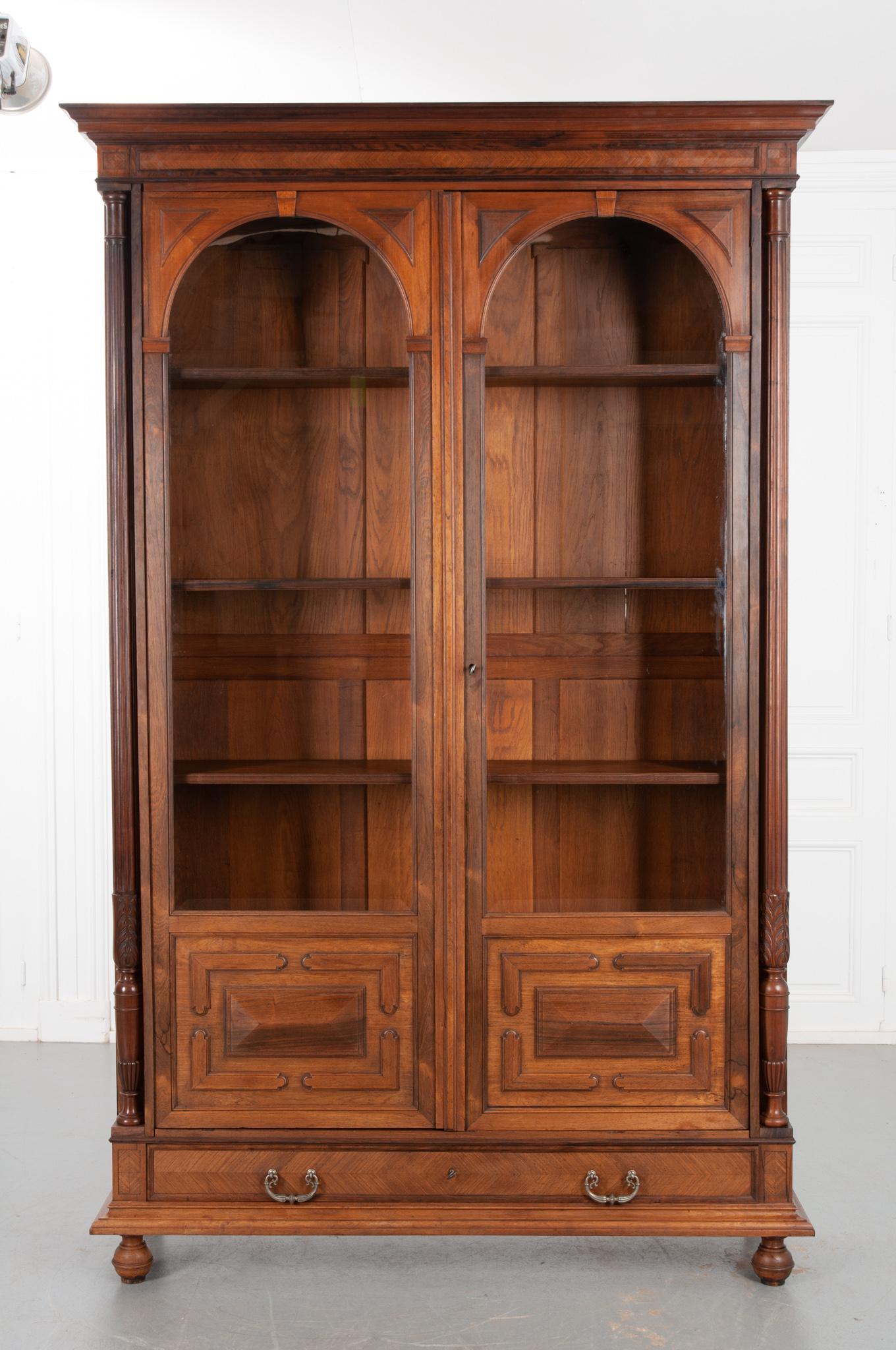 A handsome solid rosewood bibliotheque, crafted in France circa 1890. Gorgeous arched doors with beveled glass and geometric carvings accentuate the display space at the top of this bookcase. Four adjustable shelves provide plenty of space for your
