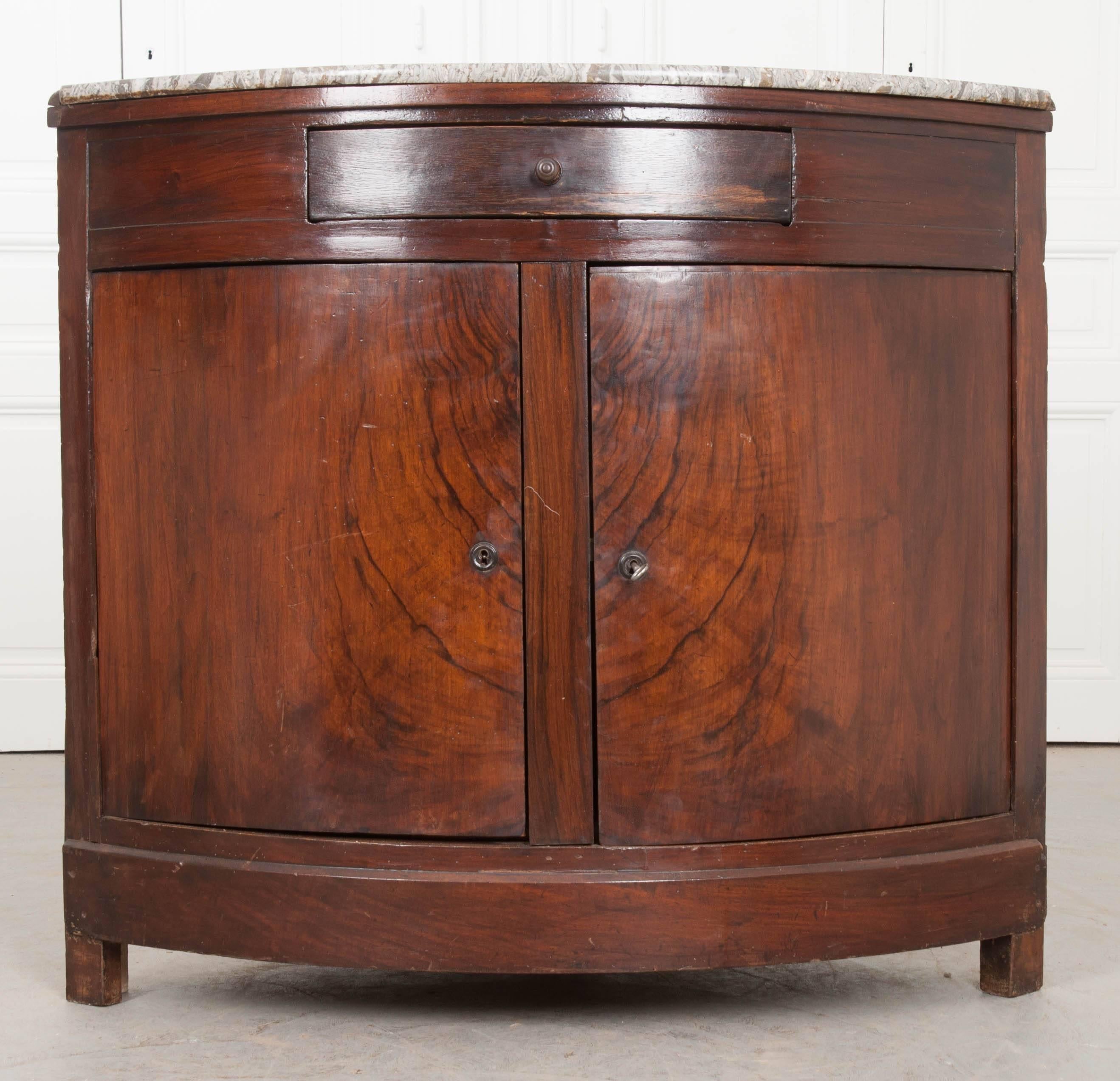 This French marble top buffet was made to fit into a corner, making a statement while maximizing storage and serving space. The rounded front has a single drawer found in the buffet’s apron, as well as two bowed doors that each have working locks.