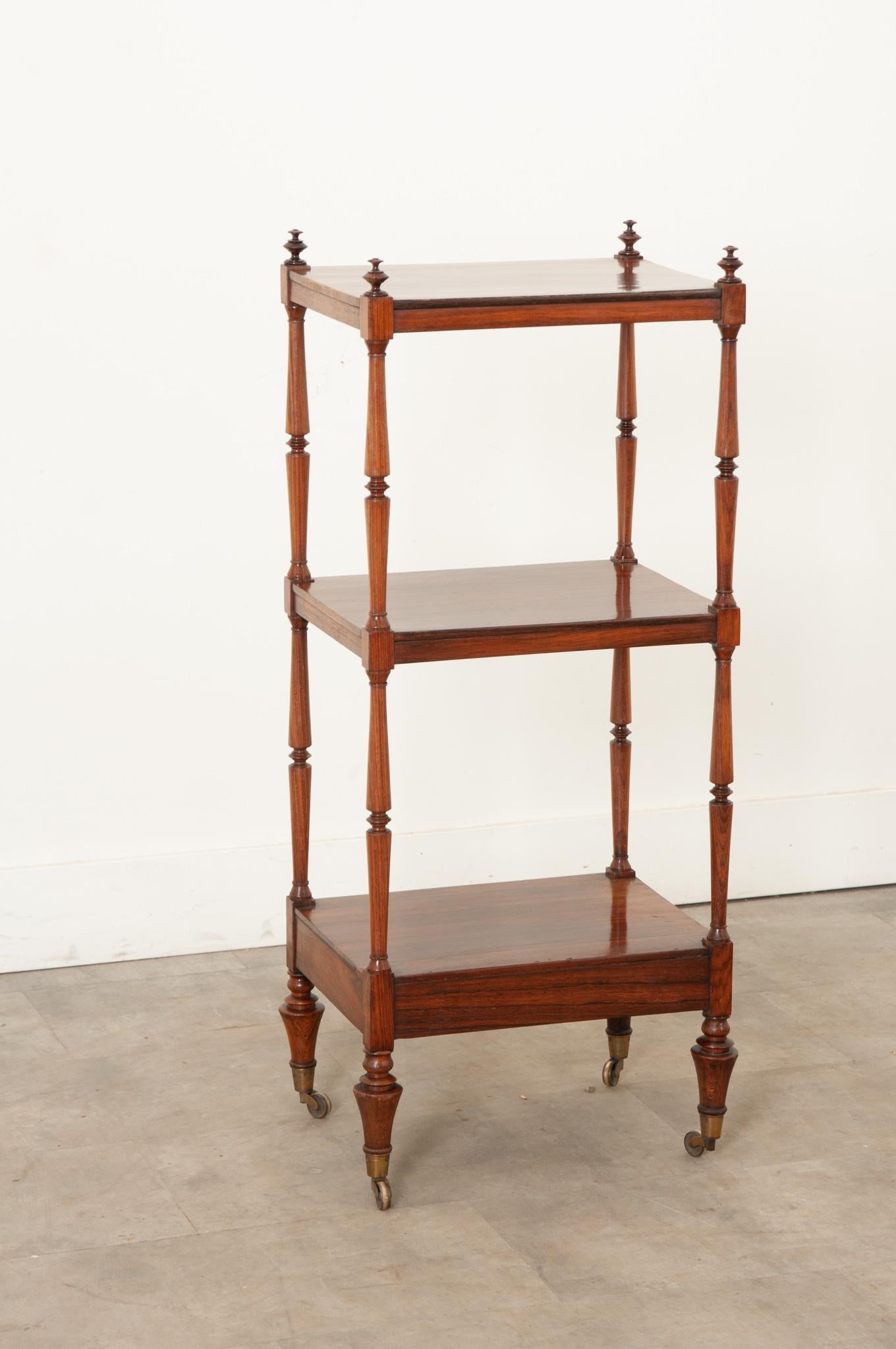 A smart etagere made of solid rosewood is the perfect addition to any interior. Topped with turned rosewood finials, three shelves are well spaced between the tall decorative table legs. The whole resting on its original casters. Be sure to take a