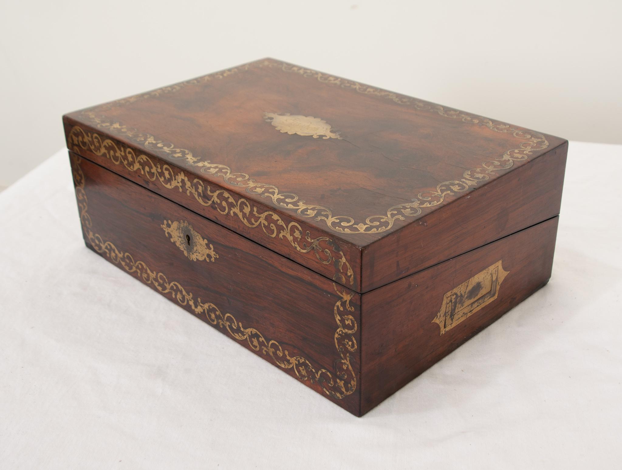 A French traveling writing box made of rosewood during the 1800’s. The exterior has an intricately detailed brass inlaid banding with an ogee cartouche in the center of the top, monogrammed “Elizabeth”. The box opens up to reveal its original sloped