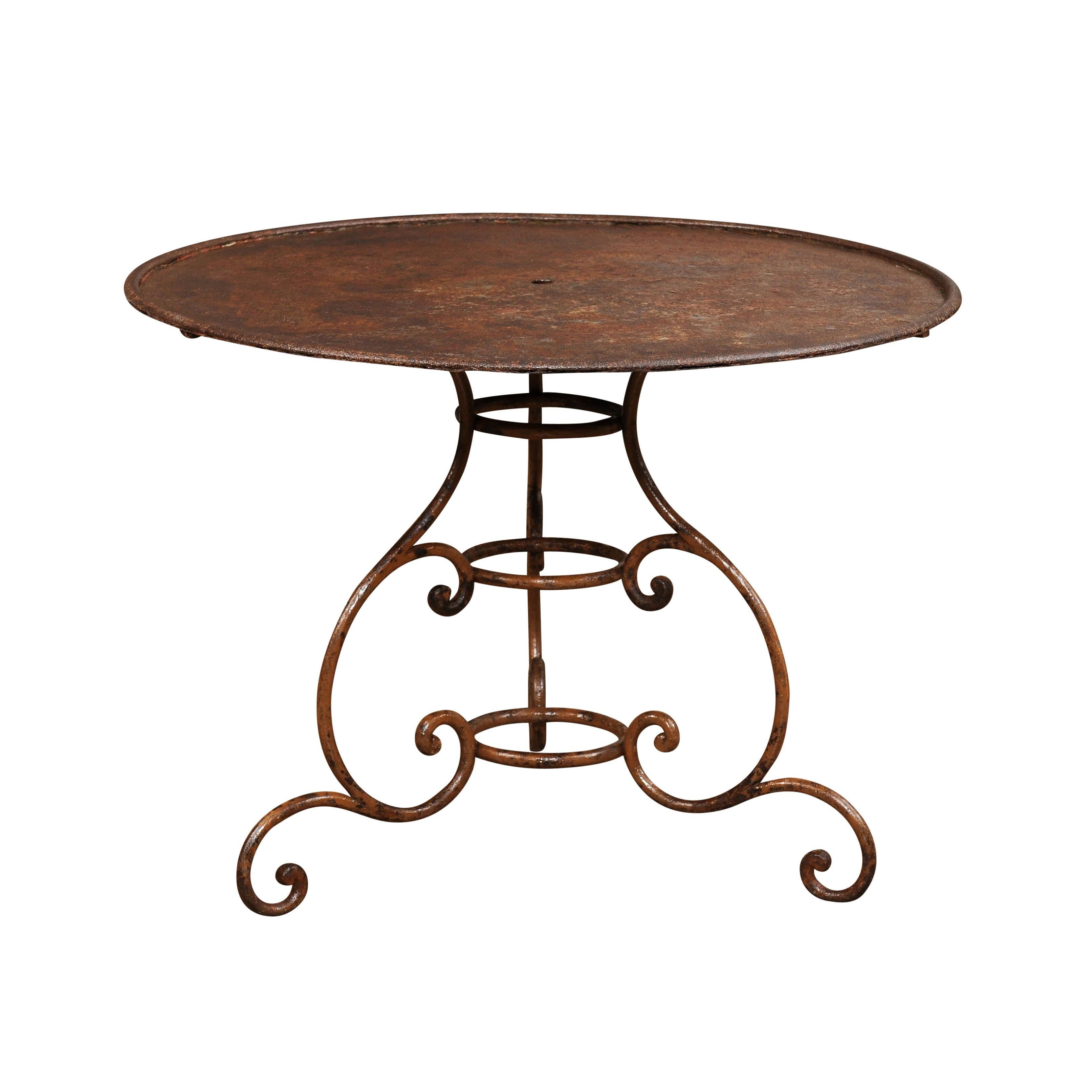 A French iron garden table from the 19th century with circular top, tripod scrolling base and great rustic character. Enhance your outdoor space with this charming French iron garden table from the 19th century. With its circular top, tripod