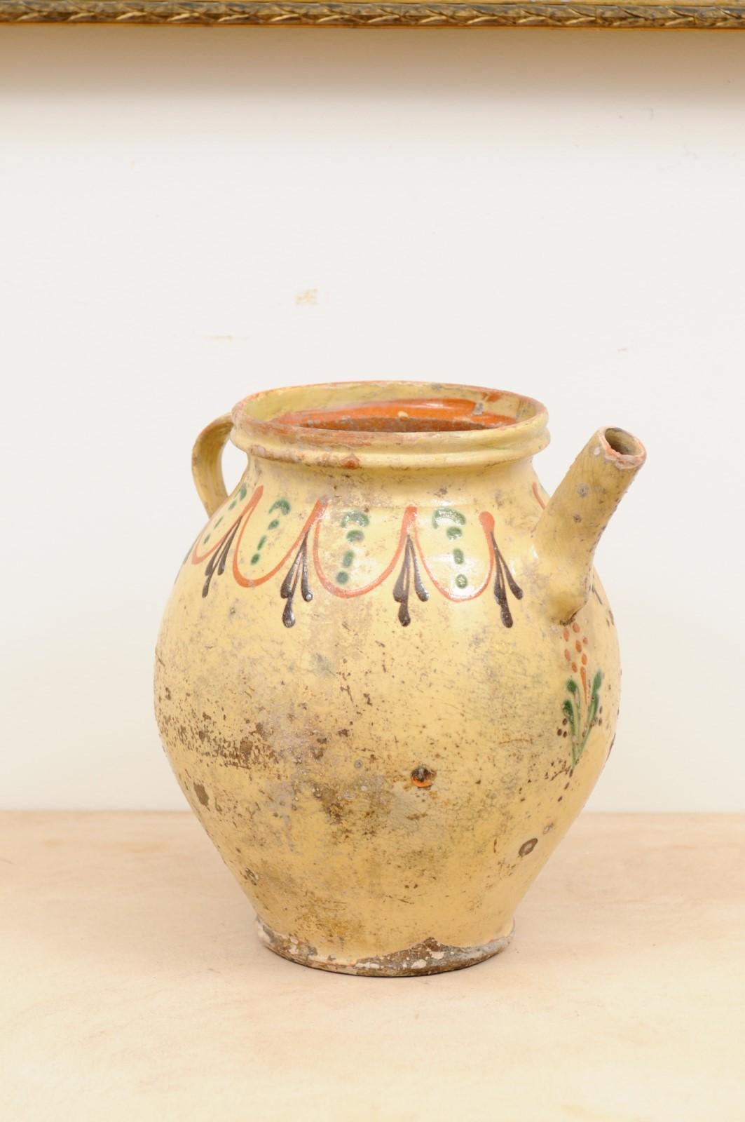 Pot à huile d'olive en poterie vernissée française du 19e siècle, avec des motifs bruns, orange et verts. Créé en France au XIXe siècle, ce pot à huile d'olive rustique présente un aspect joliment patiné, délicatement rehaussé d'une frise de motifs