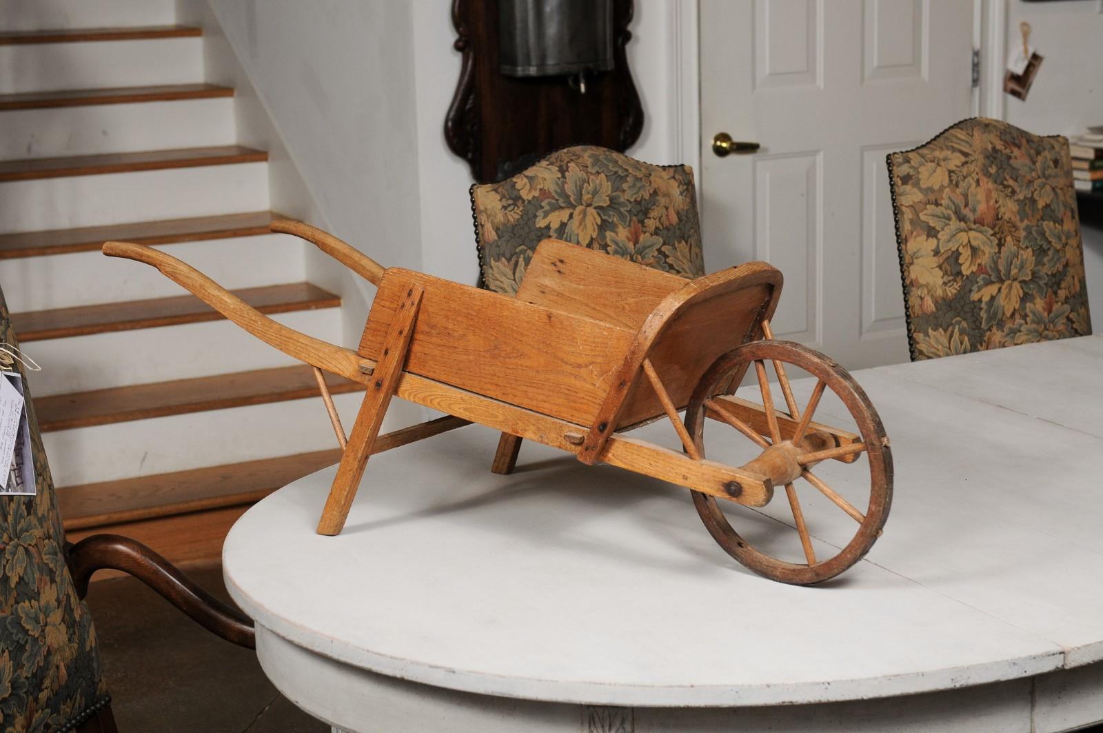A French wooden child's wheelbarrow from the 19th century, with curving handles. Created in France during the 19th century, this petite wheelbarrow will make for an excellent addition to any child's room. Boasting a nicely rustic appearance, this