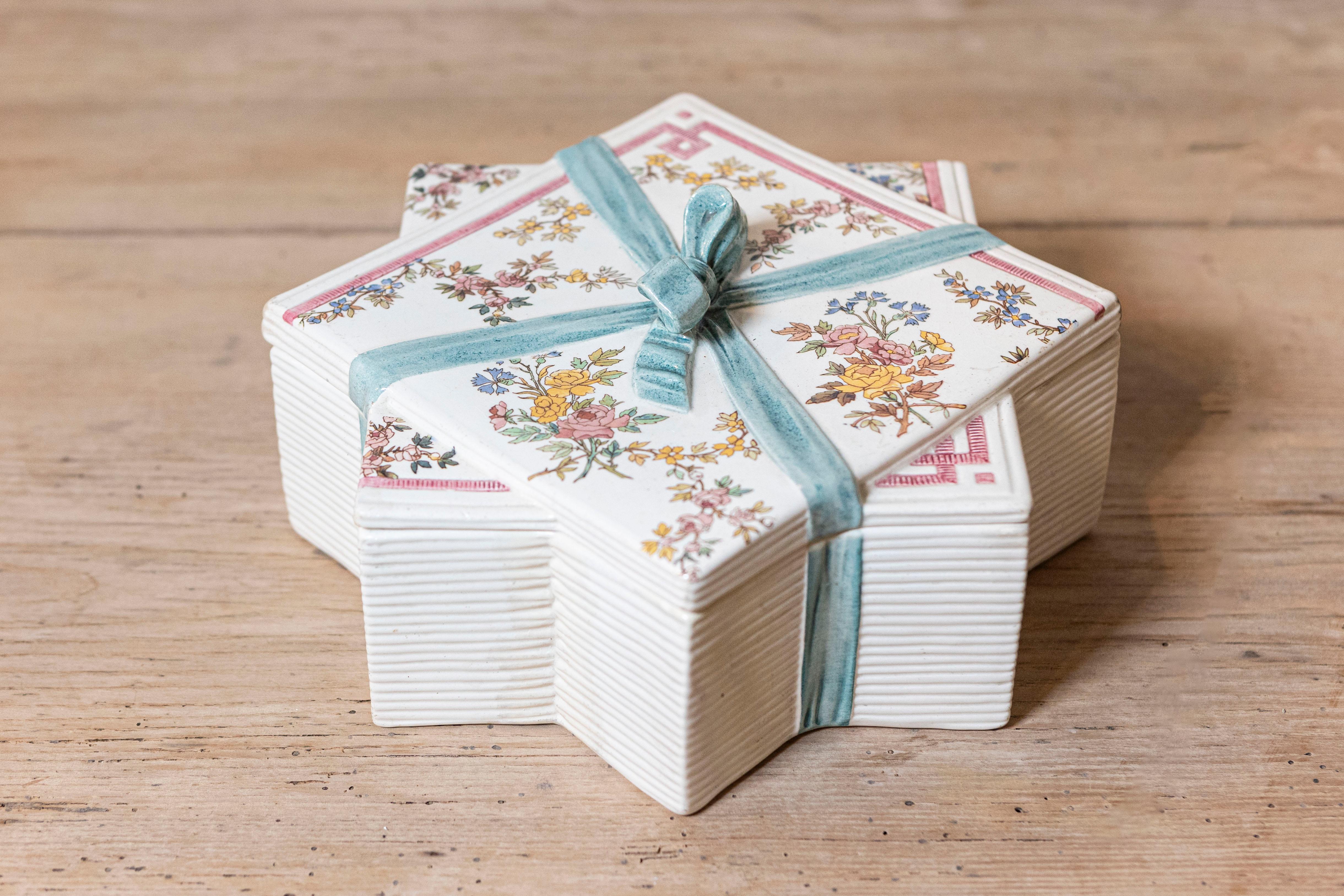 A French Sarreguemines star-shaped porcelain box from the late 19th century with floral motifs and ribbon design. Created in the Moselle department located in current Northeastern France, this porcelain box features a star shape perfectly adorned