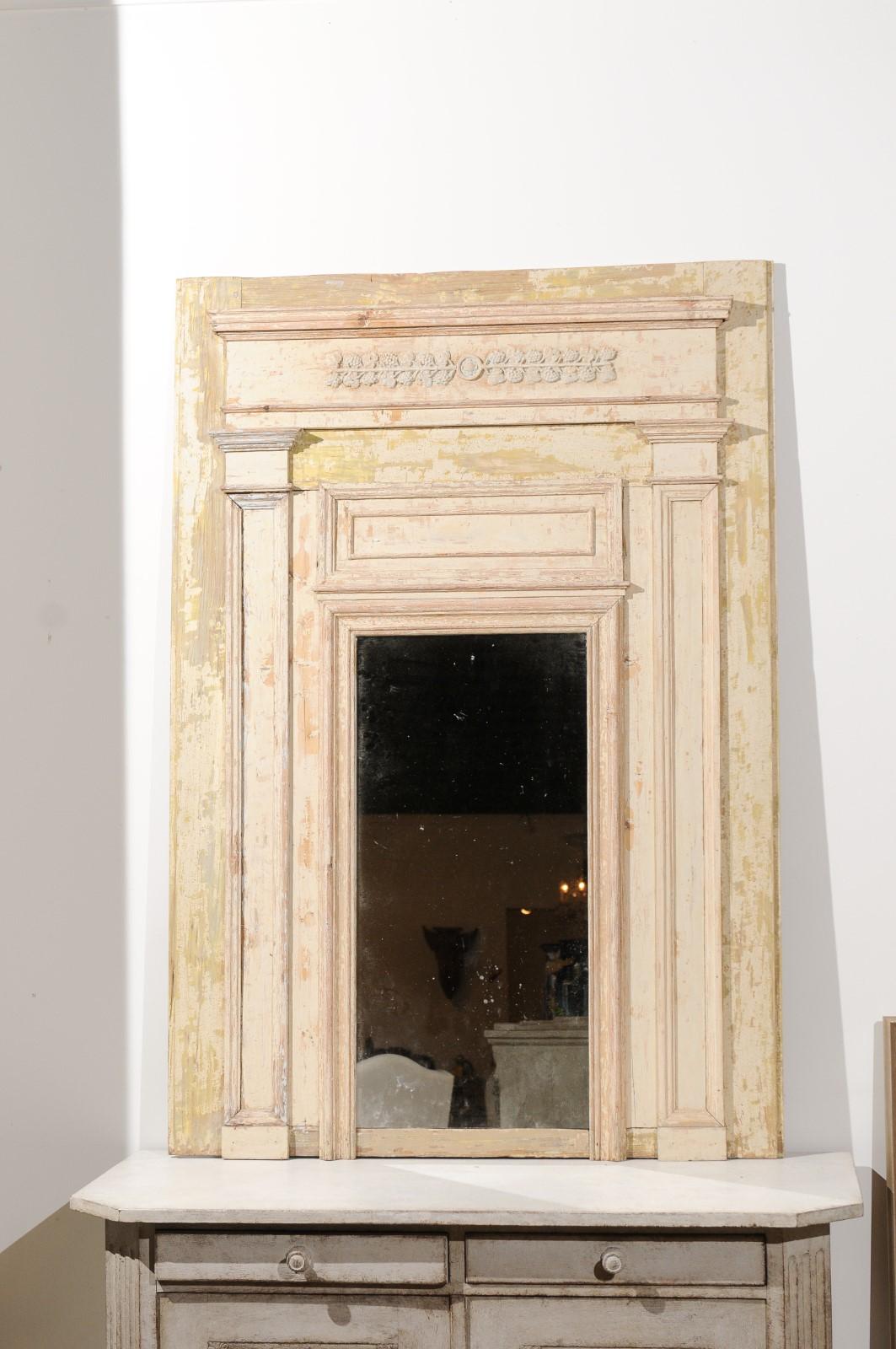 A French scraped wooden trumeau mirror from the 19th century, with carved grapes and Doric pilasters. Created in France during the 19th century, this trumeau mirror features a scraped background adorned with a portico style structure. The lintel is