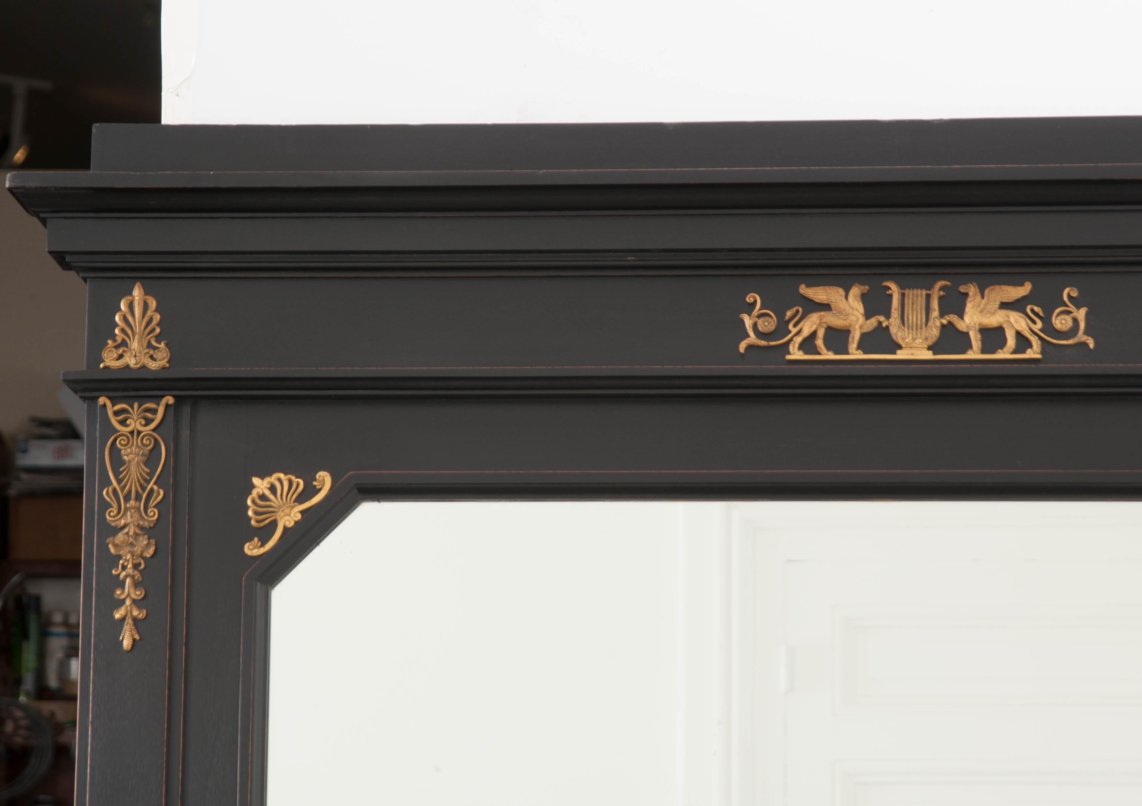 Refine your living space with this smart and sophisticated Empire style trumeau, done in ebony and brass, from 19th century France. This stately antique will command the attention of all those lucky enough to encounter it. The tall mirror retains