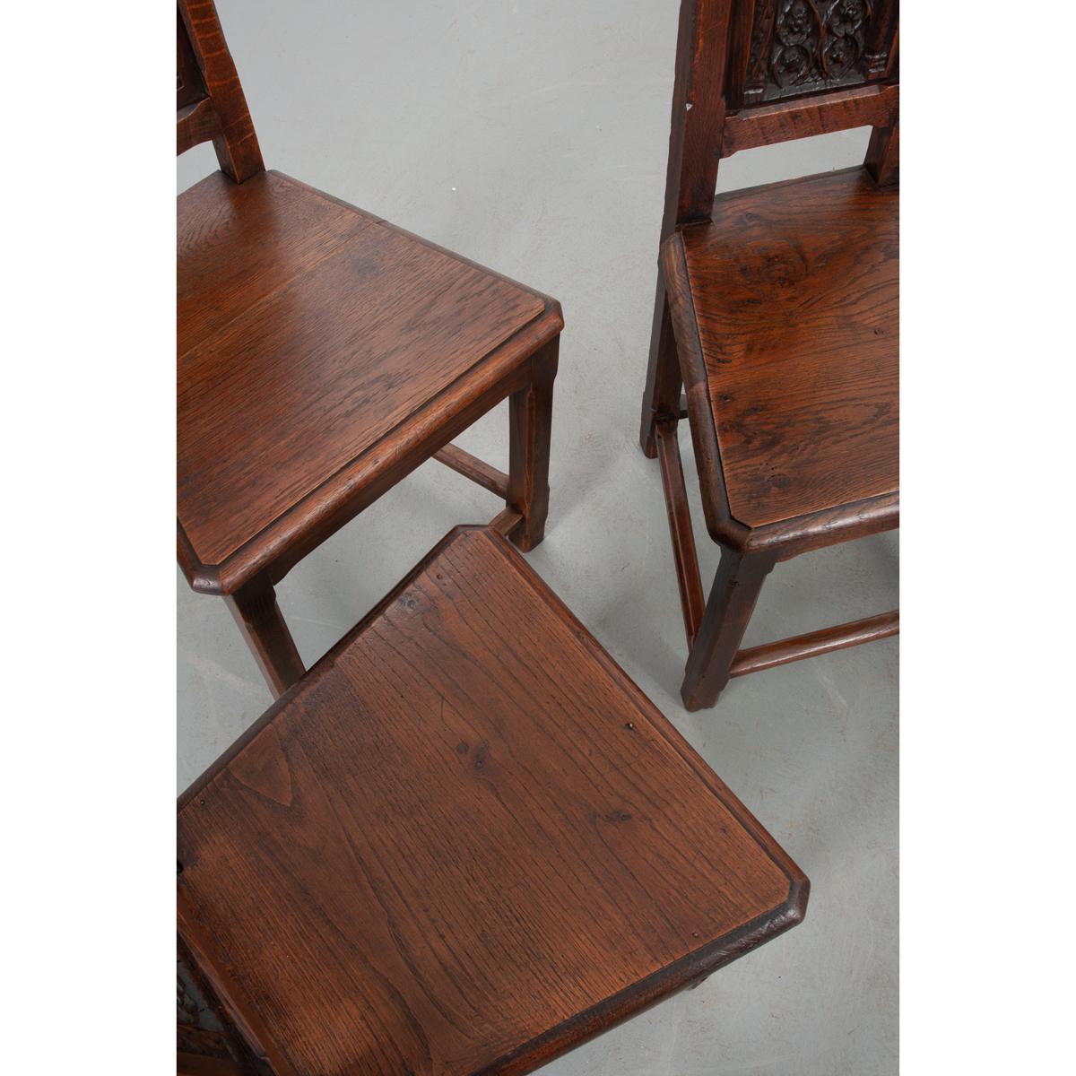 This set of remarkable Gothic style chairs are made of solid oak that has acquired a warm patina over the last two centuries. Made in France circa 1800. One chair is slightly taller than the others, suggesting it was designated for the head of the