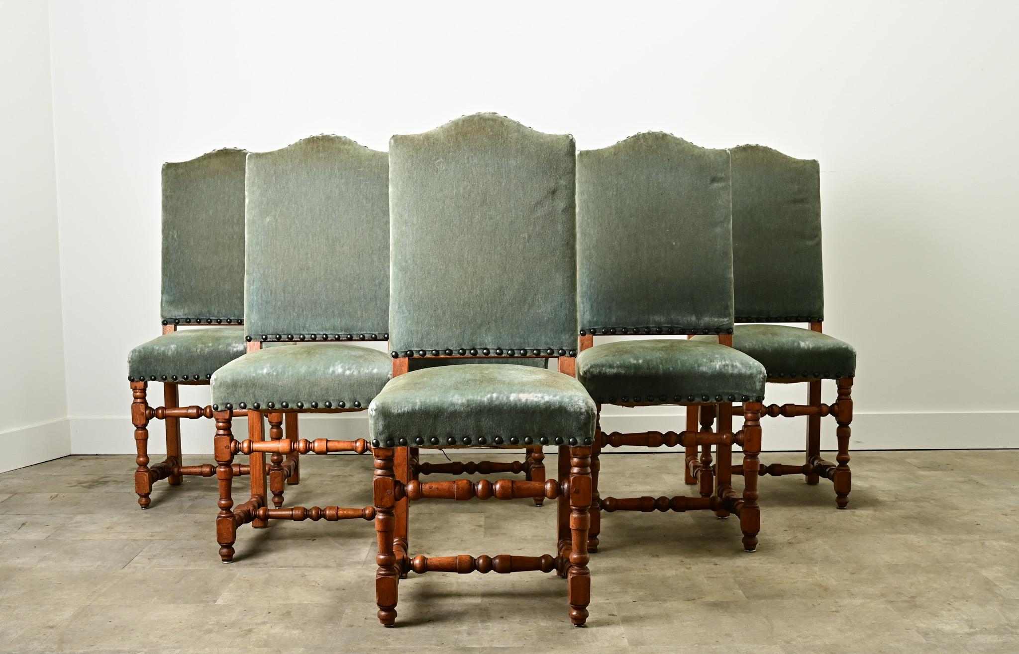 A French set of six oak dining chairs made during the 1800’s. The chair frames are made of solid oak, sturdy in design and craftsmanship. They have been upholstered in a green mohair with large patinated brass nailheads. The fabric is used and shows