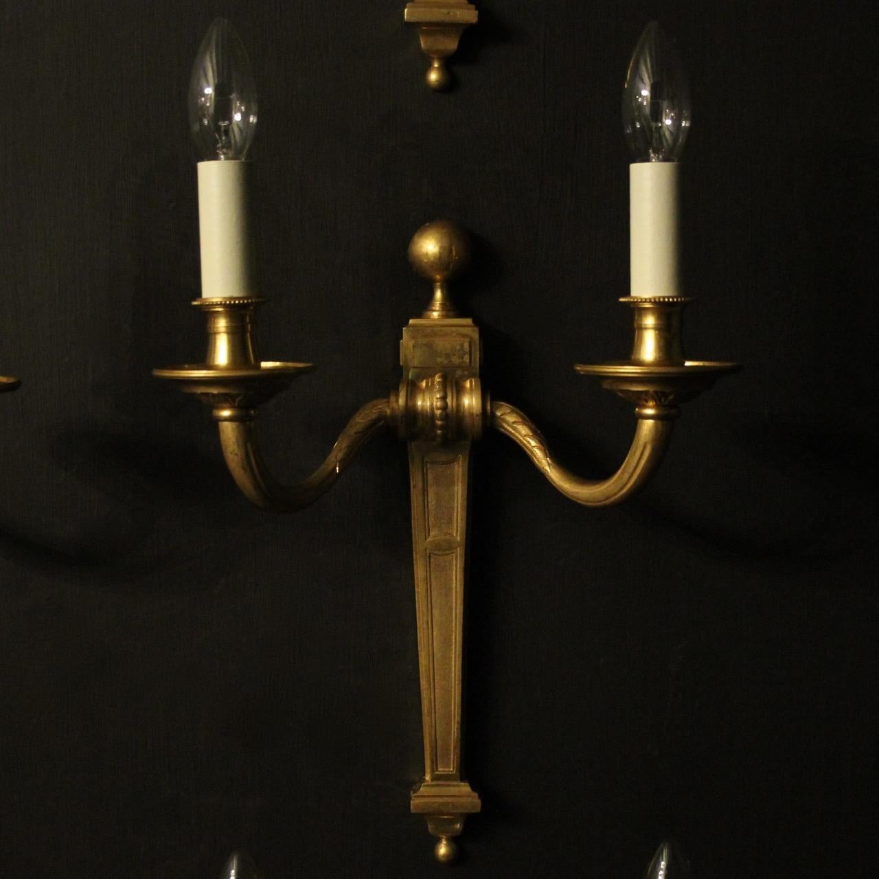 A French set of six gilded bronze twin branch antique wall lights, the tapering reeded scrolling arms with circular bobeche drip pans and decorative bulbous candle sconces, issuing from a tapering back plate with ball finial, good original
