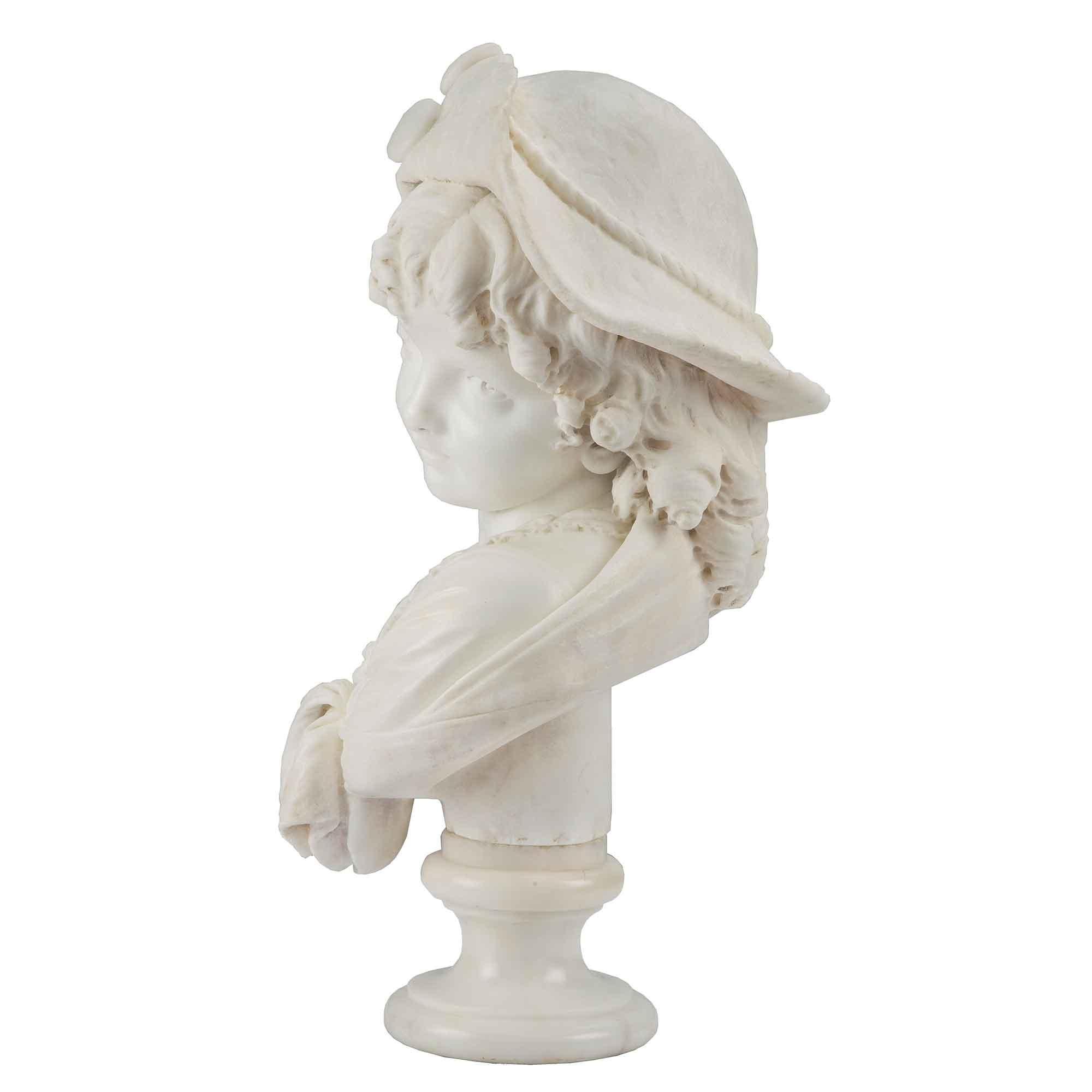 Très charmant buste en marbre blanc de Carrare signé du XIXe siècle représentant une jeune fille élégante. Élevée sur un socle circulaire, elle est vêtue d'une robe classique et porte un châle sur les épaules. Avec une expression adorable et de