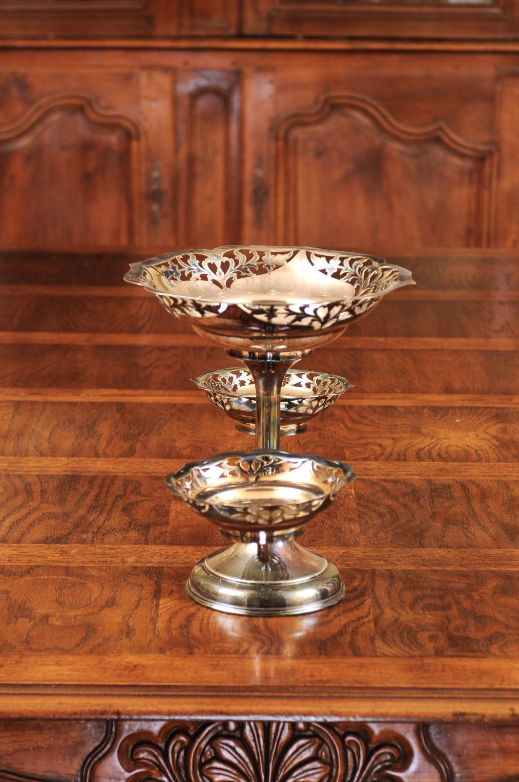 A French silver epergne from the 19th century, with pierced silver bowls and foliage motifs. Created in France during the 19th century, this silver epergne features a central shaft supporting the main bowl, adorned with pierced foliage on the outer