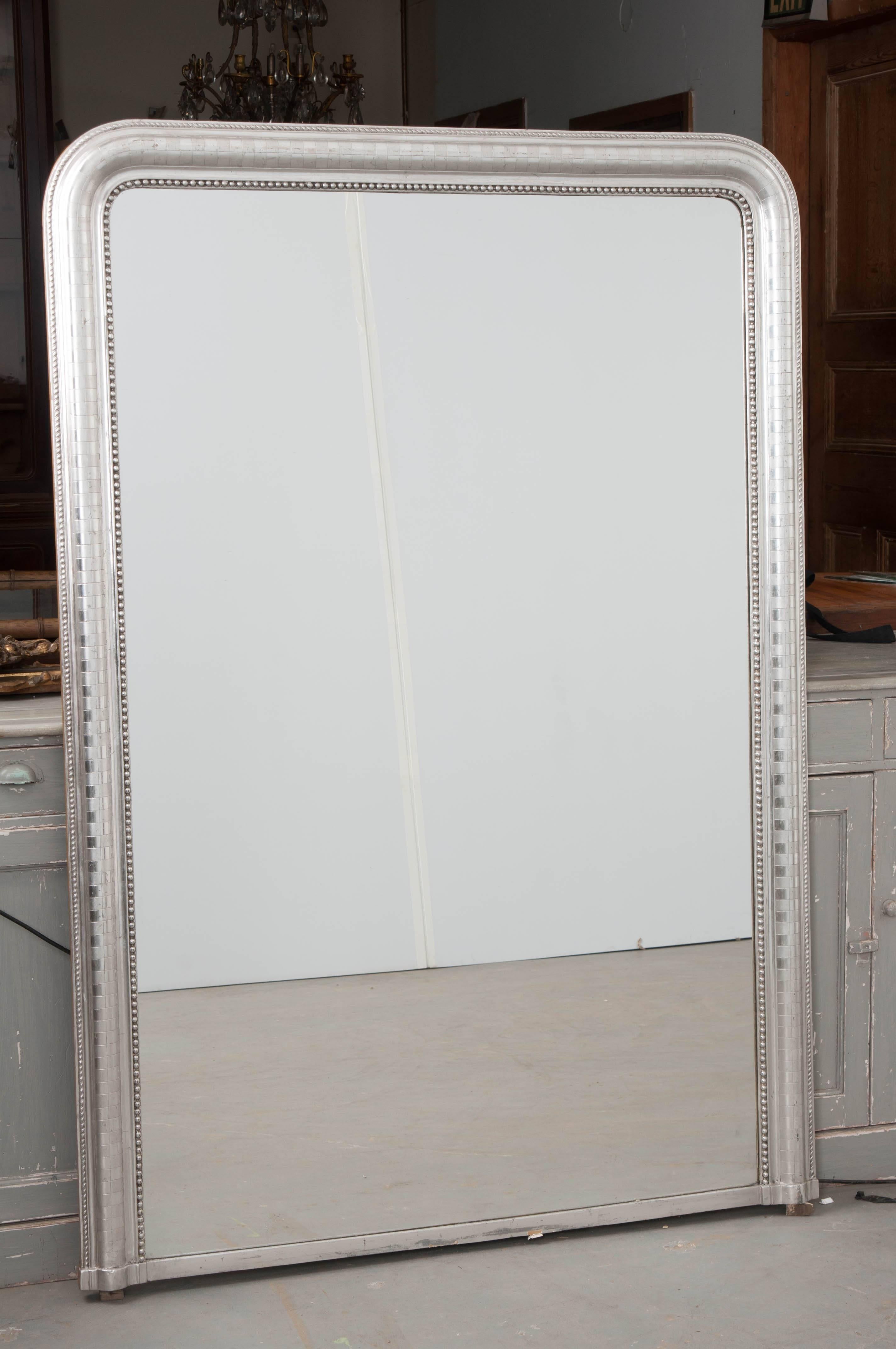 A gorgeous, large silver gilt mirror, made in France, circa 1880. This tall, wide mirror is done in the Classic Louis Philippe style. The frame has been finished in silver gilt that is in remarkable antique condition. The gilt gleams in the light