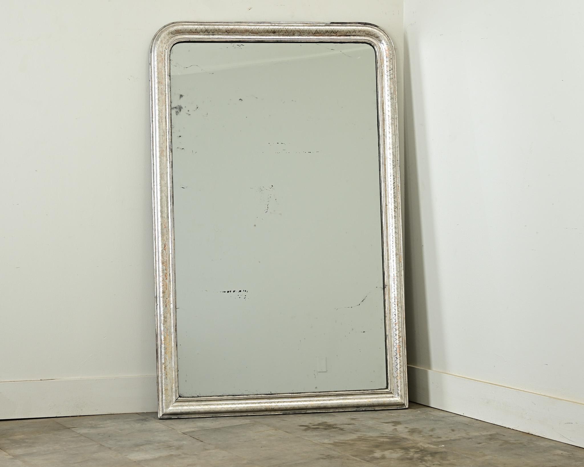 Specchio francese Louis Philippe del XIX secolo con motivo a traliccio leggermente intagliato nella cornice dorata in argento. La lastra a specchio originale è punteggiata da curiose macchie di foxing allineate in modo casuale sotto uno strato di