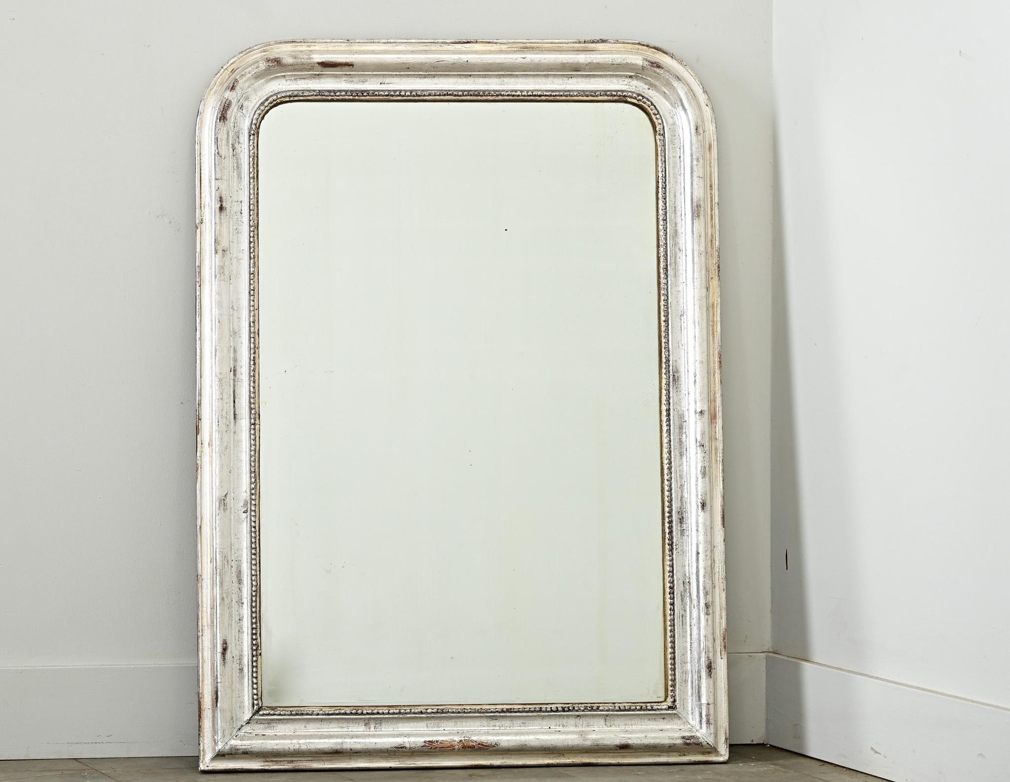 Specchio francese Louis Philippe del XIX secolo con una sobria cornice dorata in argento impreziosita da un'ossidazione scura e da una texture craquelure. Si noti che ci sono alcune crepe e aree di usura che conferiscono una patina autentica al
