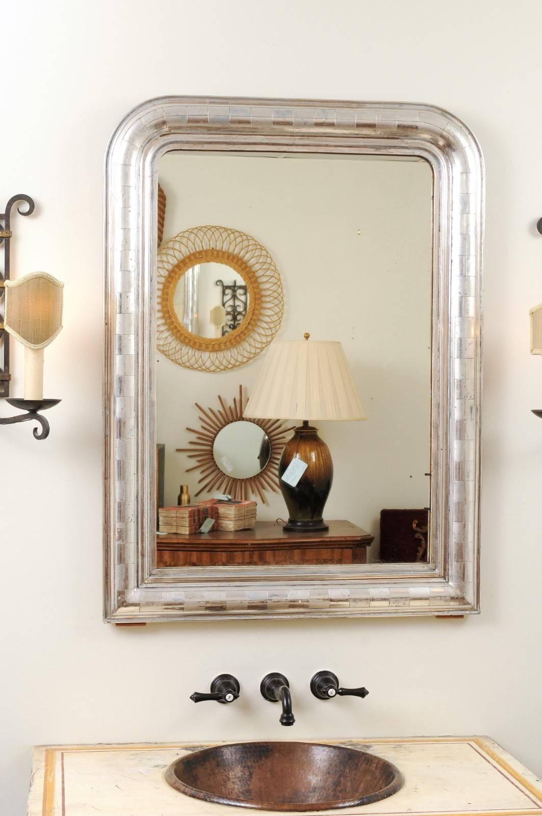 A French silver gilt Louis-Philippe mirror with alternating rectangular patterns from the 19th century. This French wall mirror features the typical silhouette of Louis-Philippe mirrors, with its rectangular frame topped with rounded corners in the