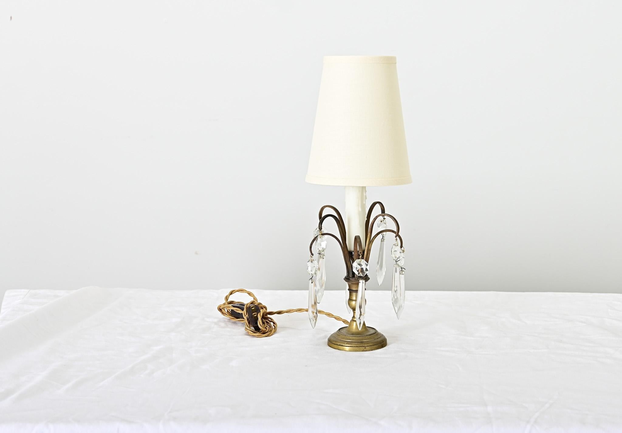 Pequeña y encantadora lámpara de sobremesa francesa de finales del siglo XIX que se eleva sobre una base de candelabro de latón con ramas de gancho de pastor y gotas de cristal para dispersar la luz. La cubierta de la vela de imitación admite una