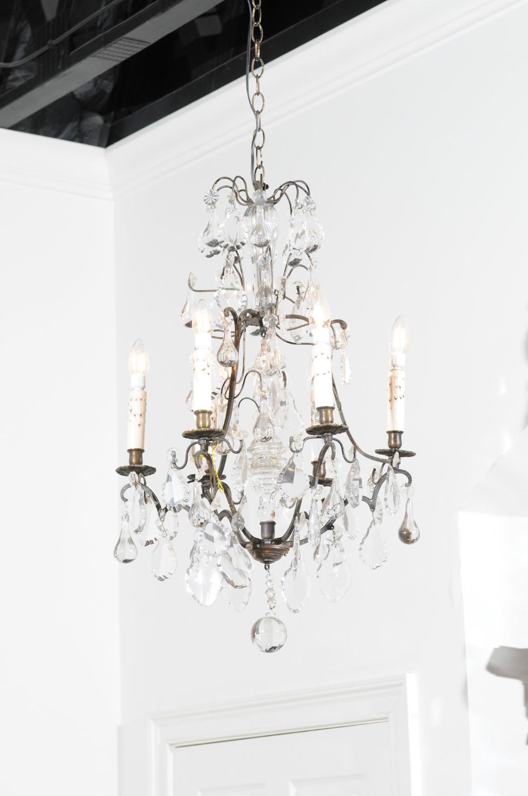 A French six-light crystal chandelier from the 19th century, with patinated brass structure, pendeloques and teardrops. Created in France during the 19th century, this crystal chandelier features an aged darkened brass armature connected to elegant
