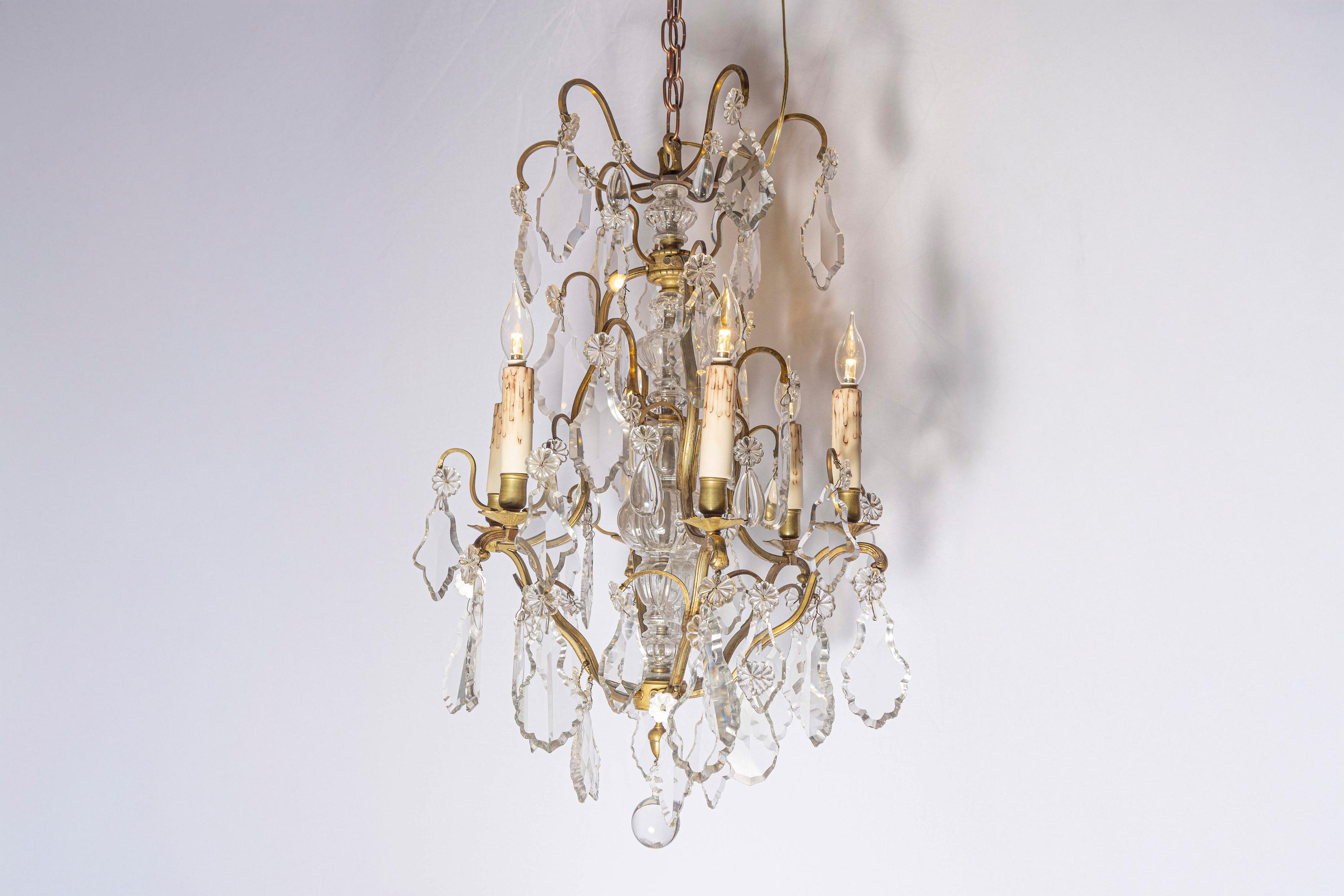 Lampadario francese a sei luci in bronzo e cristallo del XIX secolo, con bracci a spirale e bobèches a forma di fiore. Nato in Francia durante il dinamico XIX secolo, questo squisito lampadario presenta un'armatura in bronzo drappeggiata da graziosi