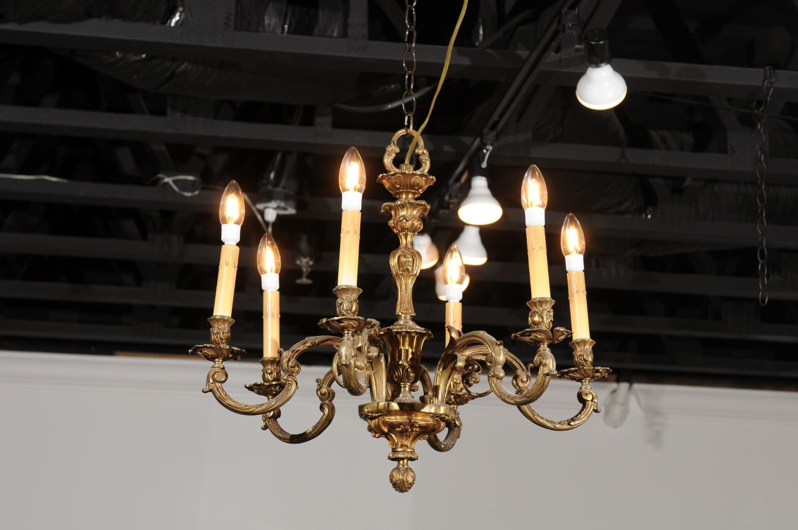A French six-light bronze chandelier from the 19th century, with foliage motifs and scrolling arms. Created in France during the 19th century, this bronze chandelier features a central column adorned with foliage and connected to six C-scrolls arms