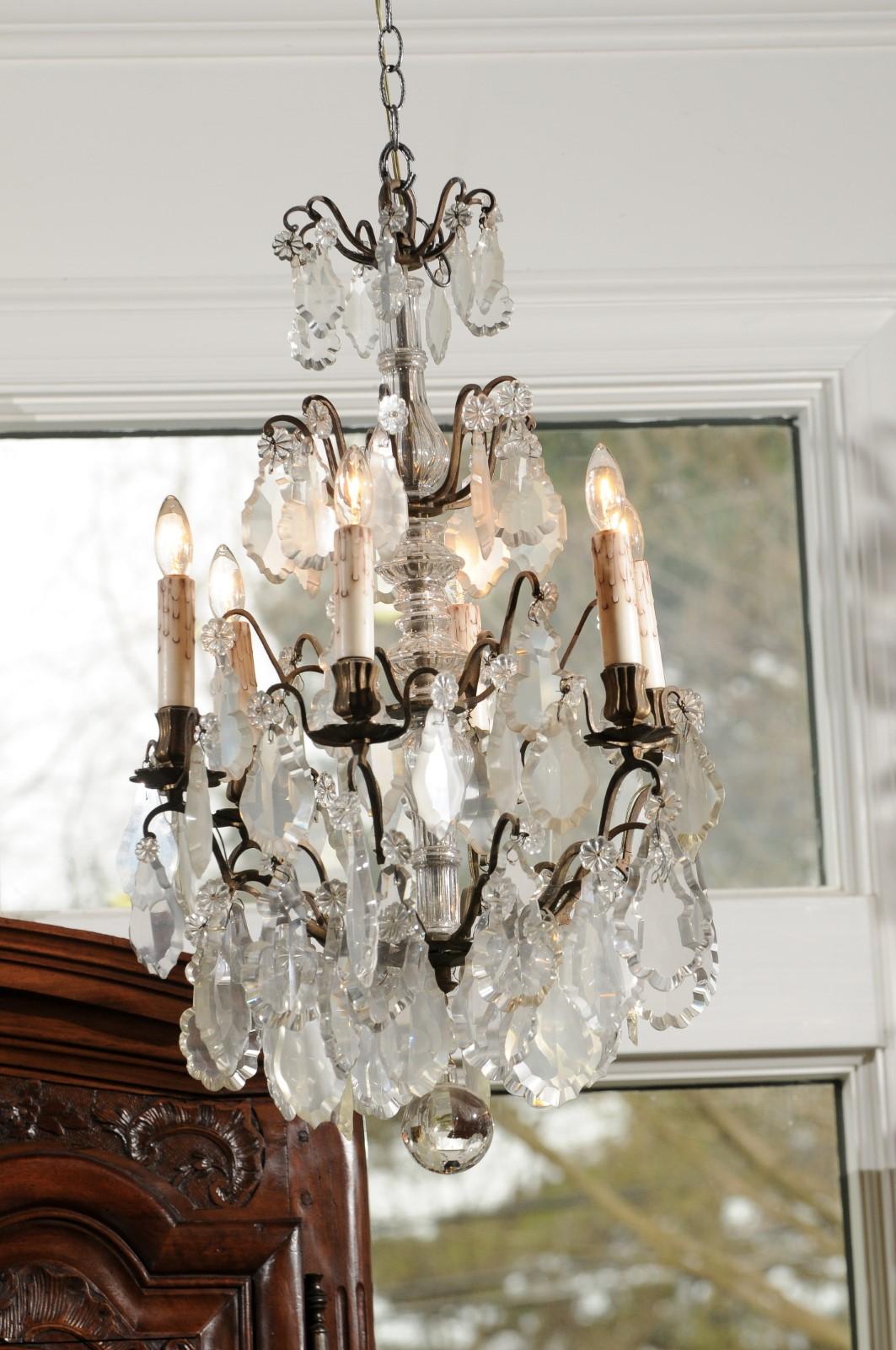 A French six-light crystal chandelier from the 19th century, with pendeloques and patinated metal armature. Created in France during the 19th century, this crystal chandelier features a central column distributing, through petite scrolls, an