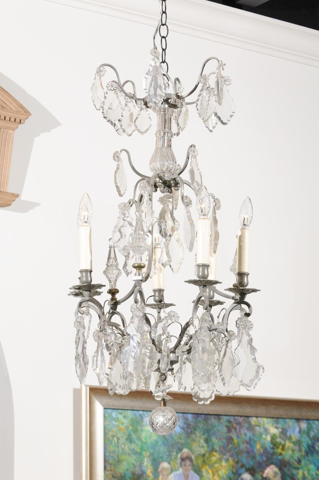 A French six-light crystal chandelier from the 19th century, with silvered iron armature. Born in France during the 19th century, this exquisite chandelier presents a tiered Silhouette made of silvered iron scrolls adorned with pendeloques, leading