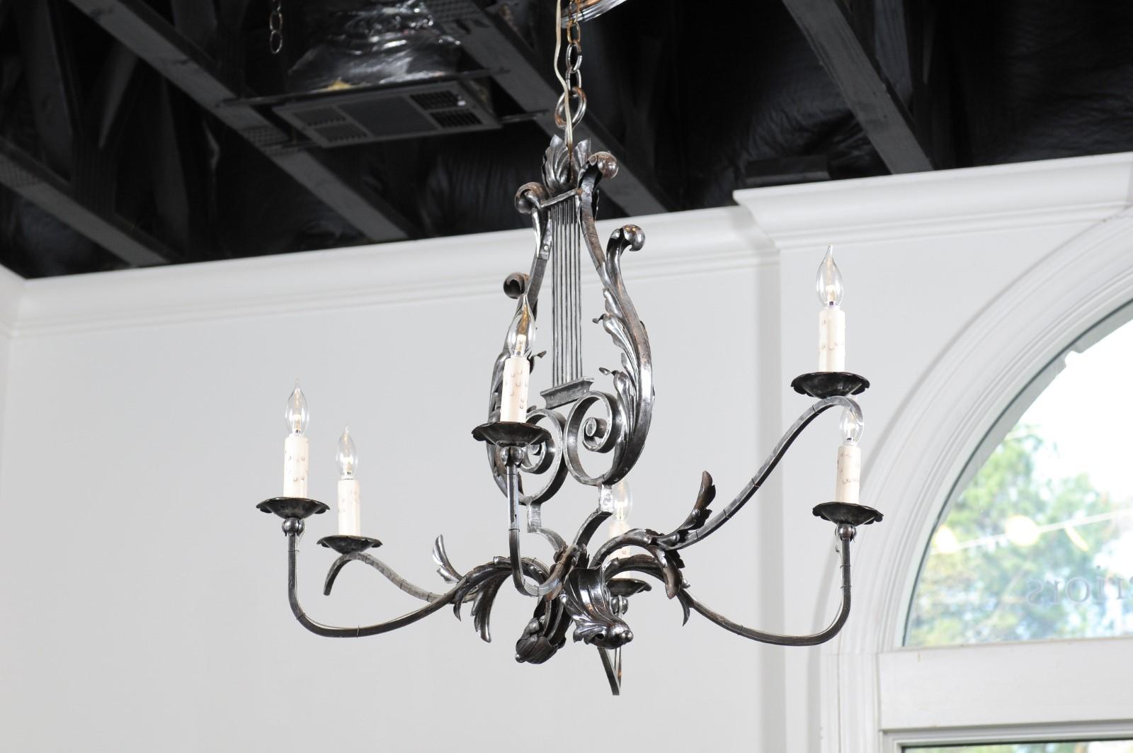 A French six-light iron chandelier from the 19th century, with lyre and acanthus leaf motifs. Born in France during the 19th century, this iron chandelier features a central lyre motif reminiscent of Apollo's personal instrument, accented with