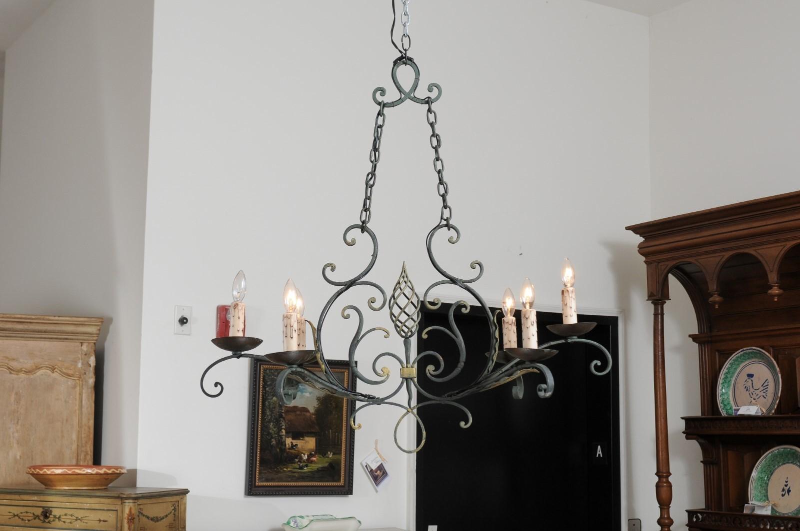 A French six-light iron chandelier from the 19th century, with spiral motif, gilt accents and scrolling arms. Created in France during the 19th century, this six-light chandelier features an iron armature presenting profiled links connected to two