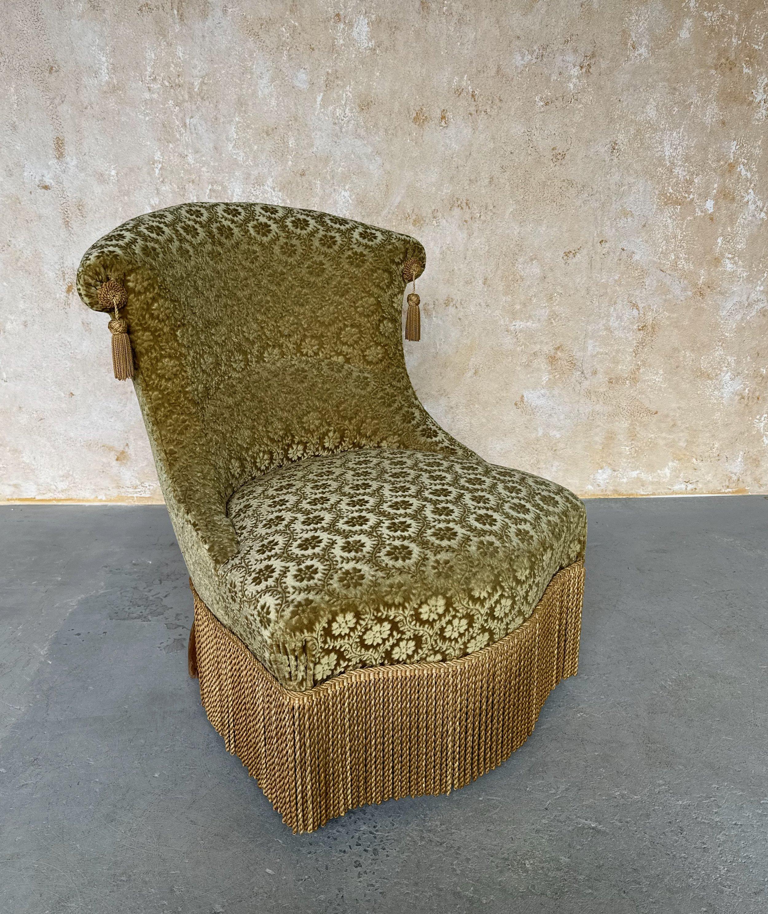 This elegant French Napoleon III slipper chair  is upholstered in a plush floral patterned gold velvet with tassel adornments and matching bullion fringe. The beautifully curved back makes it incredibly comfortable. With dimensions of 30 inches
