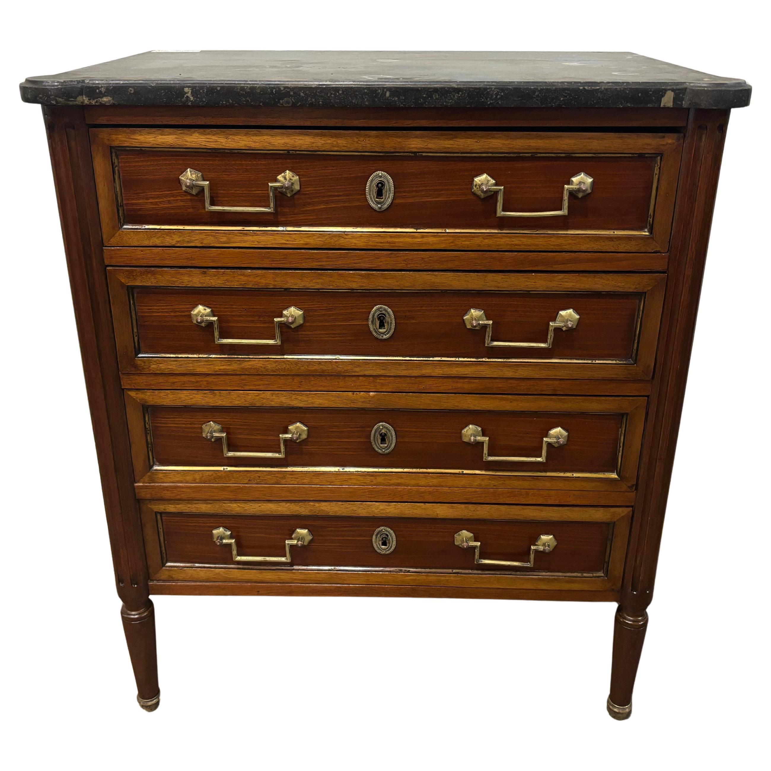 Ce petit coffre de style Louis XVI est en acajou avec des tiroirs entourés de laiton et un plateau en marbre noir. Il est très élégant et parfait pour un petit coin ou à côté d'un lit.