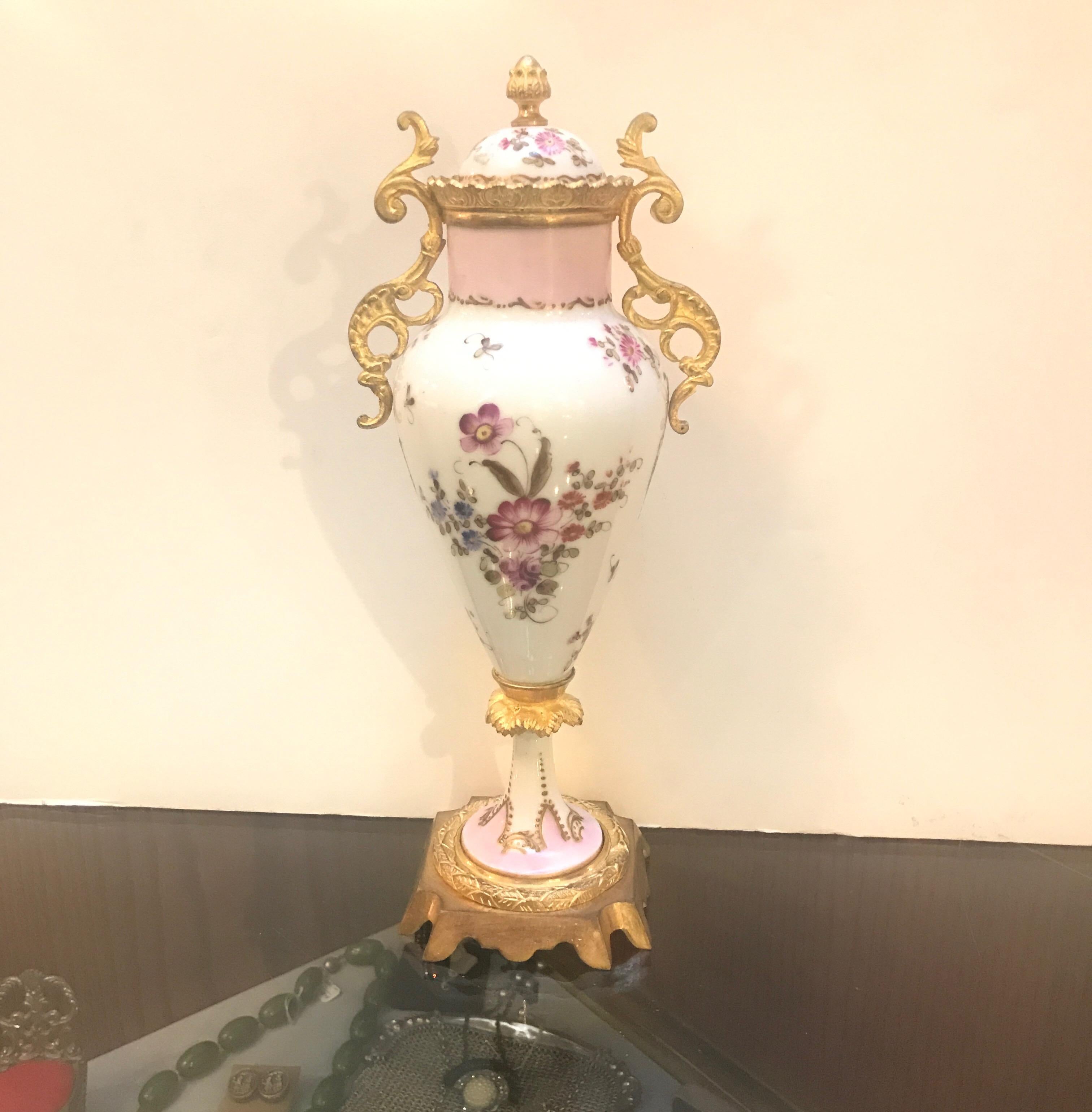 Graceful hand painted porcelain urn with lid. The raised gilt cartouche with a female figure in country scene artist signed. The back with hand painted floral decoration.