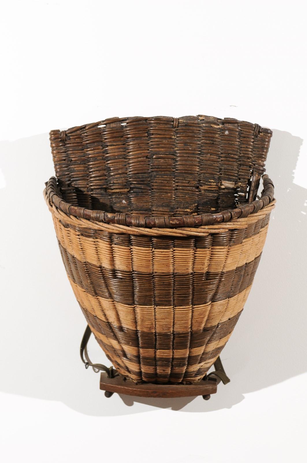 A French 19th century small wicker grape harvesting basket from the Burgundy town of Chablis. This two-toned harvesters basket features its two leather straps, used to help the workers carry it on their back and allowing them to pick up the grapes