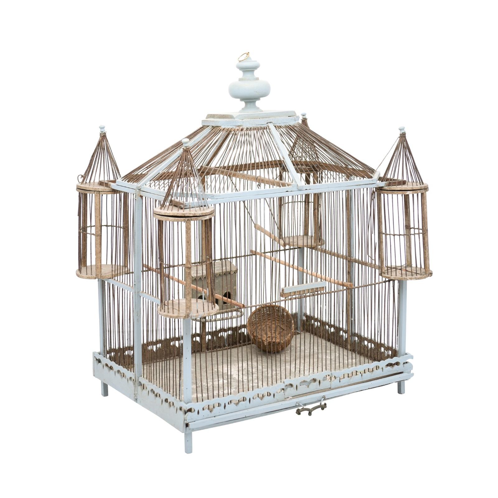 A French soft blue painted wood and metal castle inspired bird cage from the 19th century, with turrets, turned finial, petite wicker nest and rustic character. Created in France during the 19th century, this decorative bird cage features a