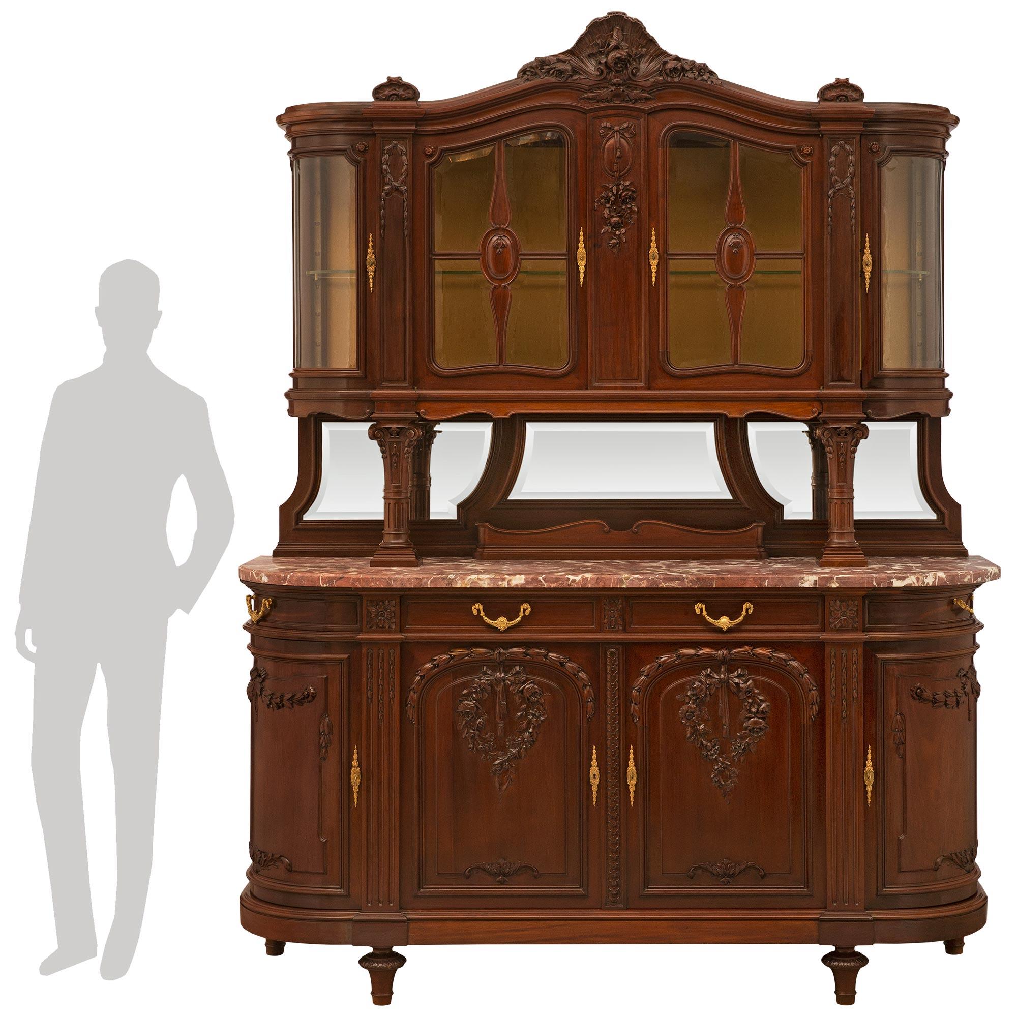 An attractive and high quality French late 19th century solid mahogany buffet with the original hutch. The buffet is raised by four tapered toupie shaped carved supports below the mottled frieze with curved ends. Each of the four doors, with ormolu