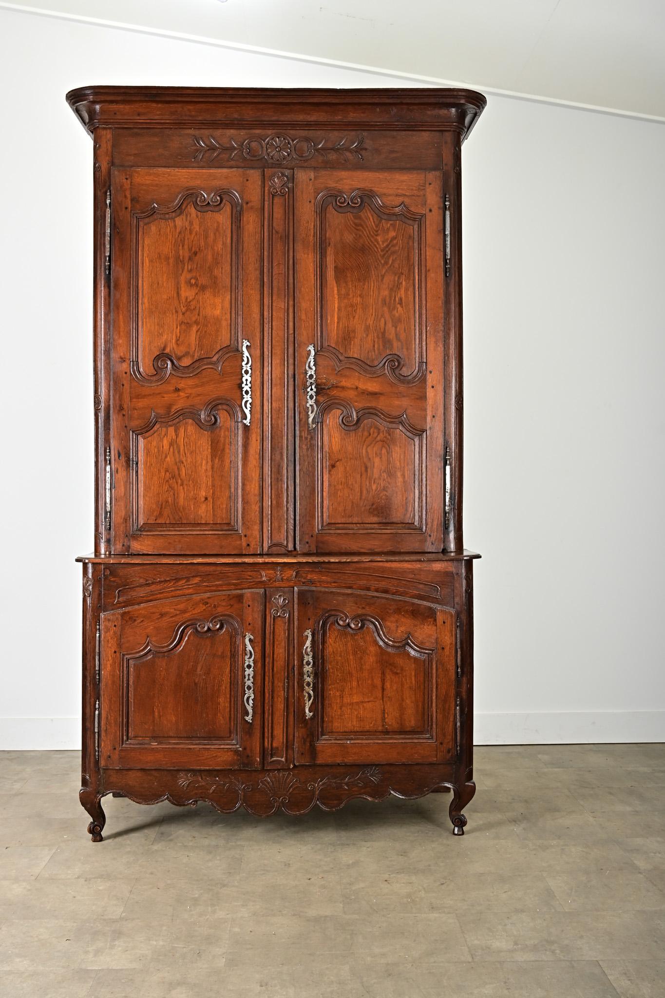 A French solid oak buffet à deux corps from the 19th century, Louis XV in style, with baroque carvings to add depth to the paneled doors, and serpentine apron that together give this large storage piece its historic character. Under the linear crown