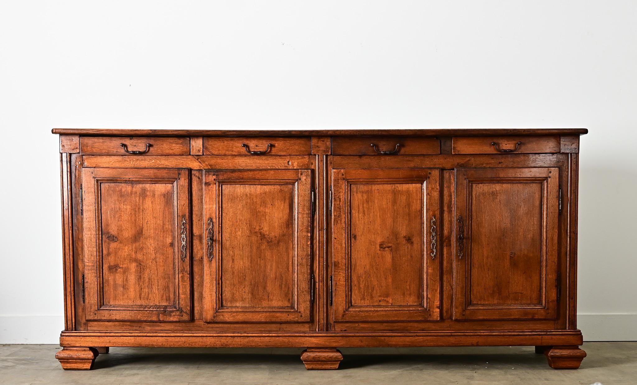 Cette enfilade française en chêne massif du XIXe siècle de style Transitionnel a de la présence et du caractère pour ancrer n'importe quel espace avec des tons de bois caramel et une patine foncée sur le cas spacieux de quatre tiroirs et quatre
