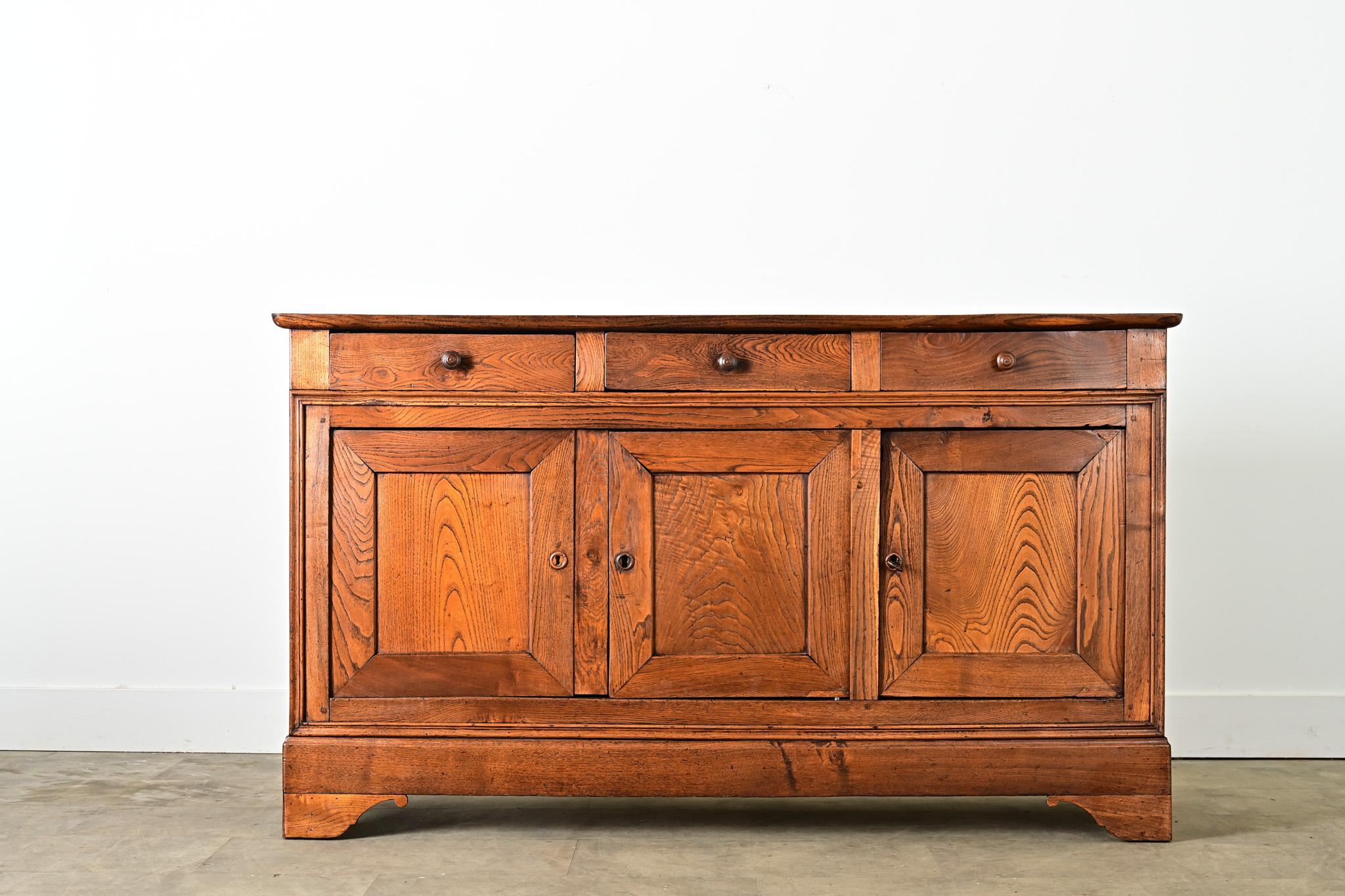 Questa enfilade francese in rovere massiccio del XIX secolo Louis Philippe esprime un grande carattere grazie alle tonalità luminose del legno e alle venature pittoriche che animano la cassa rettilinea di tre cassetti su tre ante. Le tavole