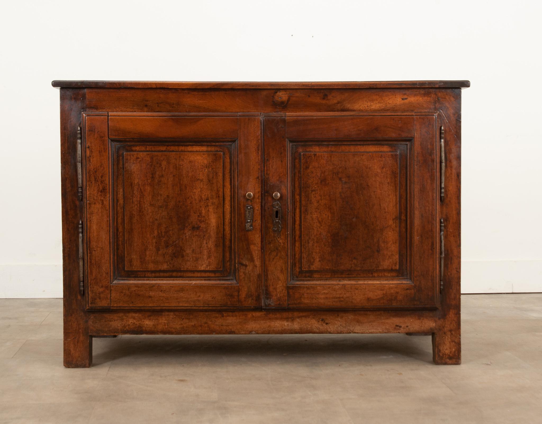 A French 19th century walnut two-door buffet that offers considerable storage space. Hand-crafted in France circa 1850, it features a rectangular top sitting above two impressive doors, adorned with carved recessed panels, elongated double hinges,