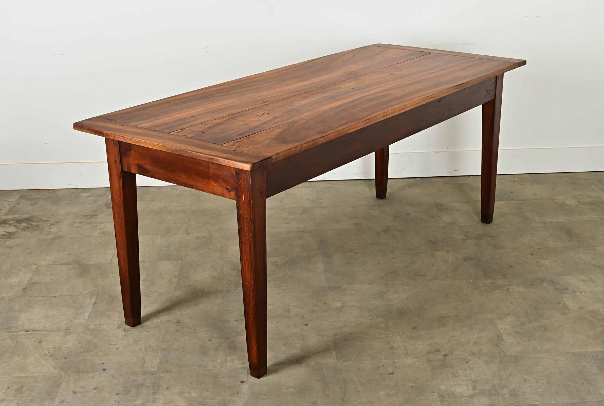 Cette table de ferme rustique d'origine française, vers 1860, peut facilement accueillir six convives. Les magnifiques planches de noyer, parsemées de têtes de chevilles carrées, sont patinées et finies avec des extrémités en planche à pain sur une