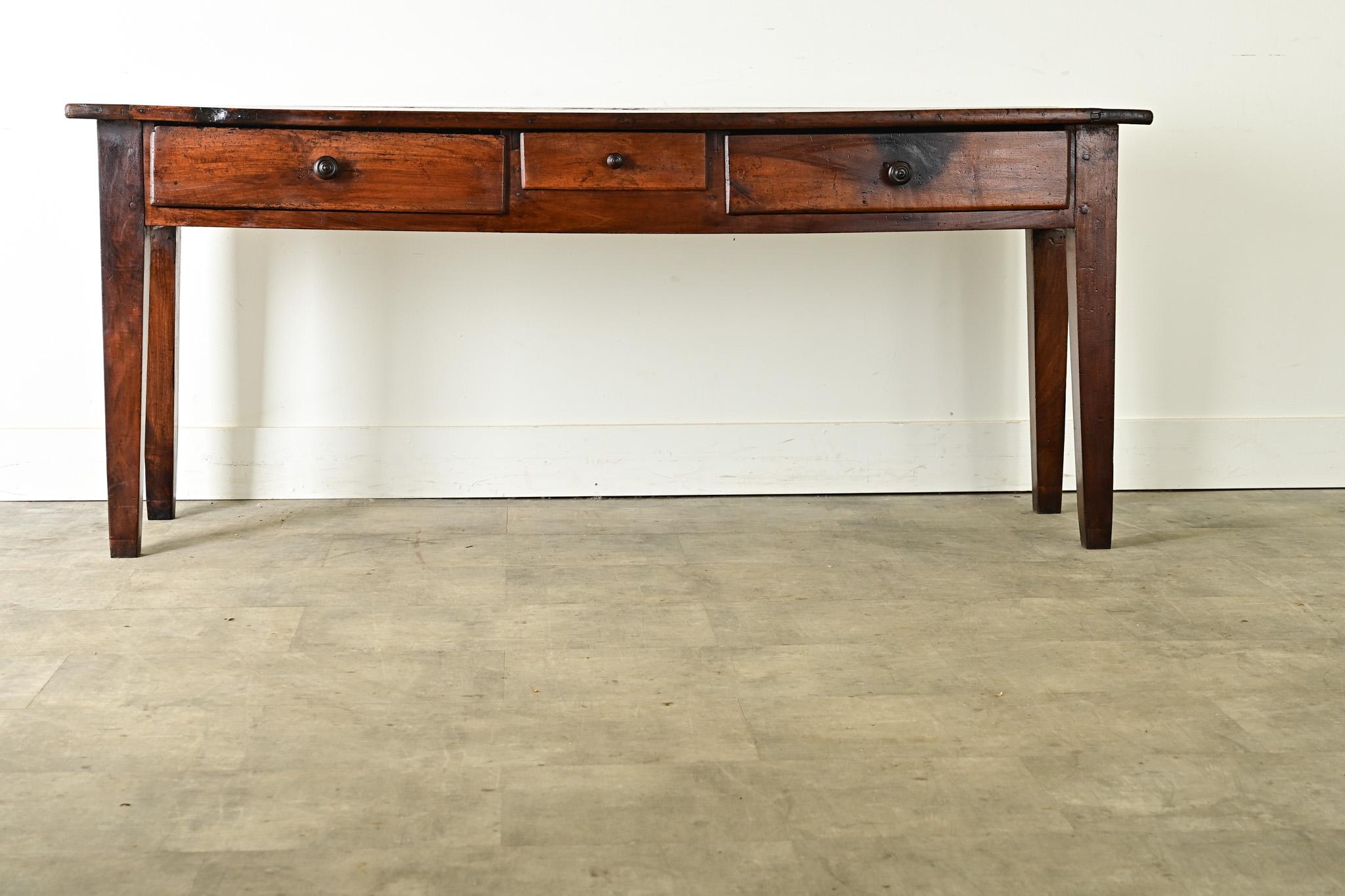 This rustic console table, or server, was hand-crafted of solid walnut in France, circa 1860. The thick planks of the top have incredible texture, a rich patina, and breadboard arrangement. A few “honest repairs” to fill holes in the planks are