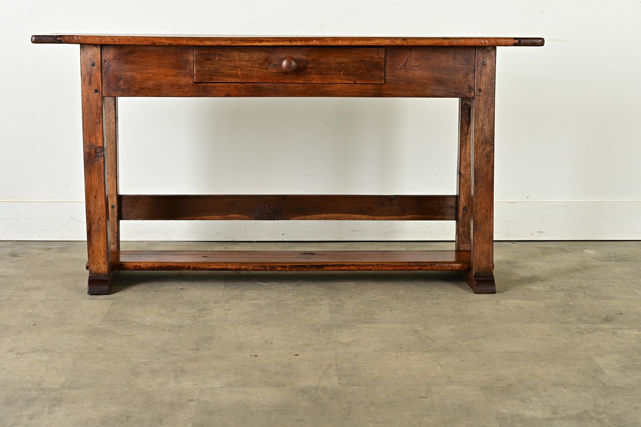 A French country house server from the 19th century crafted in walnut with abundant rustic charm. The planks of the top surface show knots and wavy grain texture–well patinated from nearly two centuries of use–framed by breadboard ends. One shallow